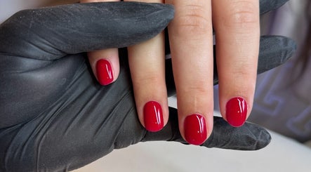 Manicure with red nails at Annabelle’s Beauty, Camberley, England, GB. Nails held by gloved hands.