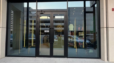 Entrance of SHUFFLE Gents Salon Hessah District in Al Asimah Governate, KW, with sleek glass doors.