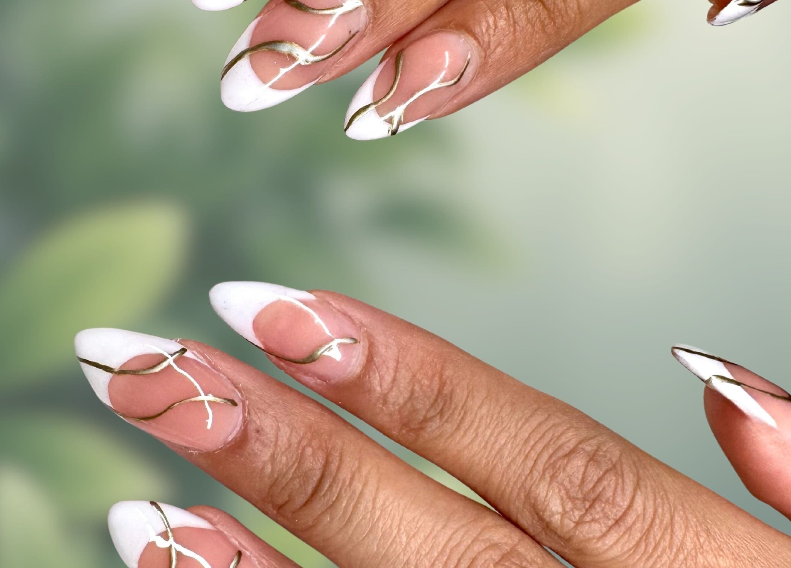Elegant nail design at Afterglow Beauty, Cambridge, England, GB showcasing intricate white and gold accents.