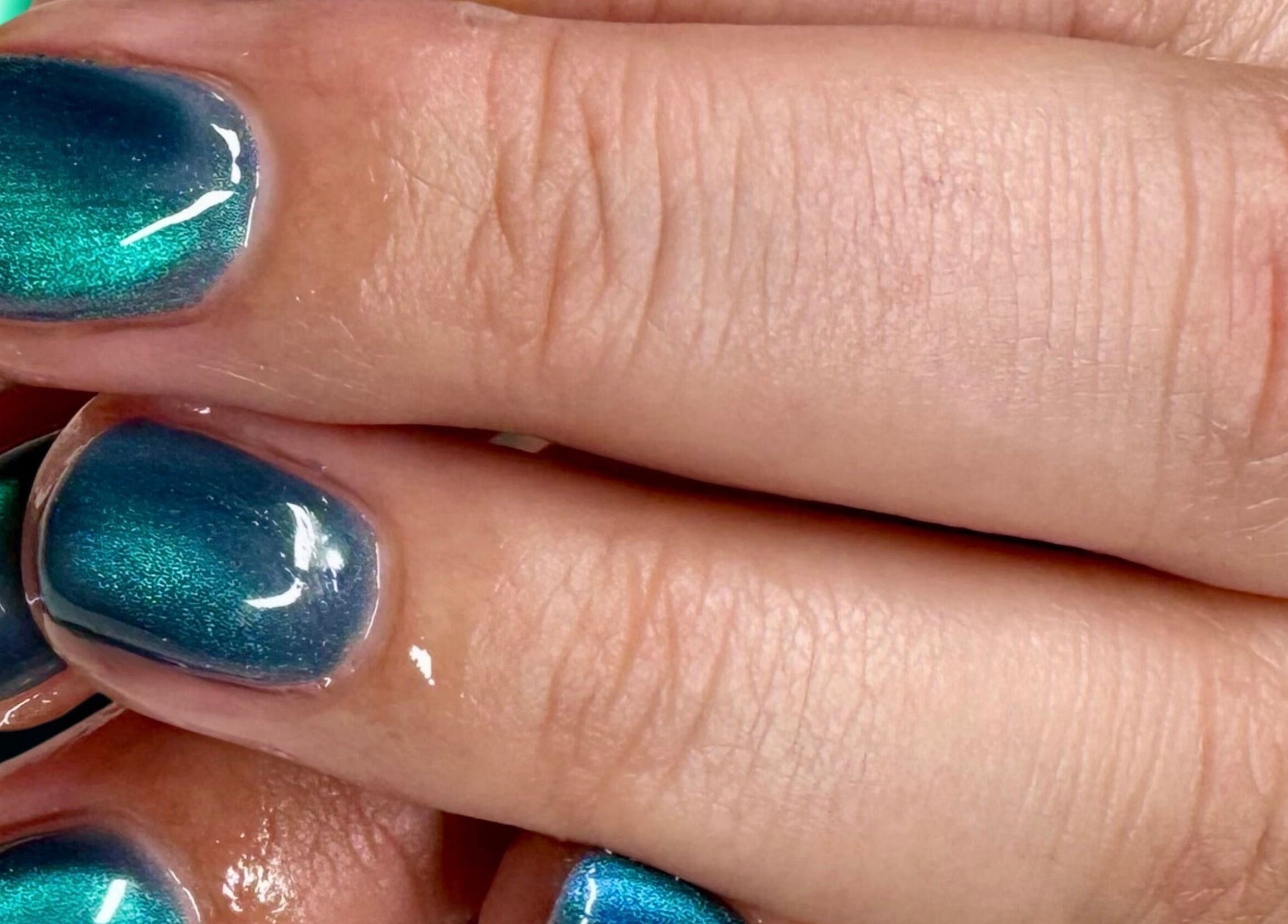 Metallic green manicure at Afterglow Beauty, Cambridge, England, GB. Elegant nail art enhancing beauty.