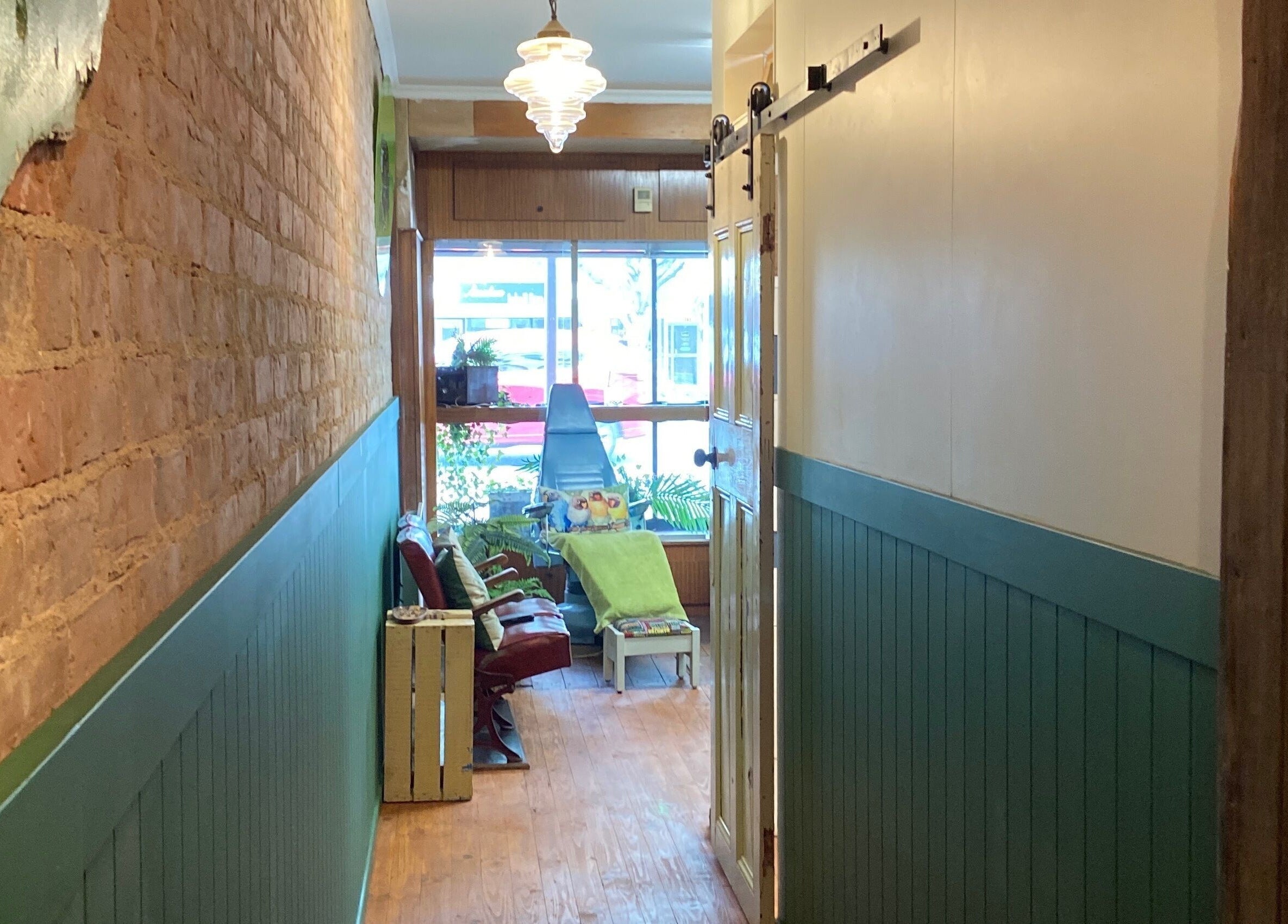 Inviting hallway at The Beauty Bach Invers, Invercargill, showcasing rustic brick and green panel walls.