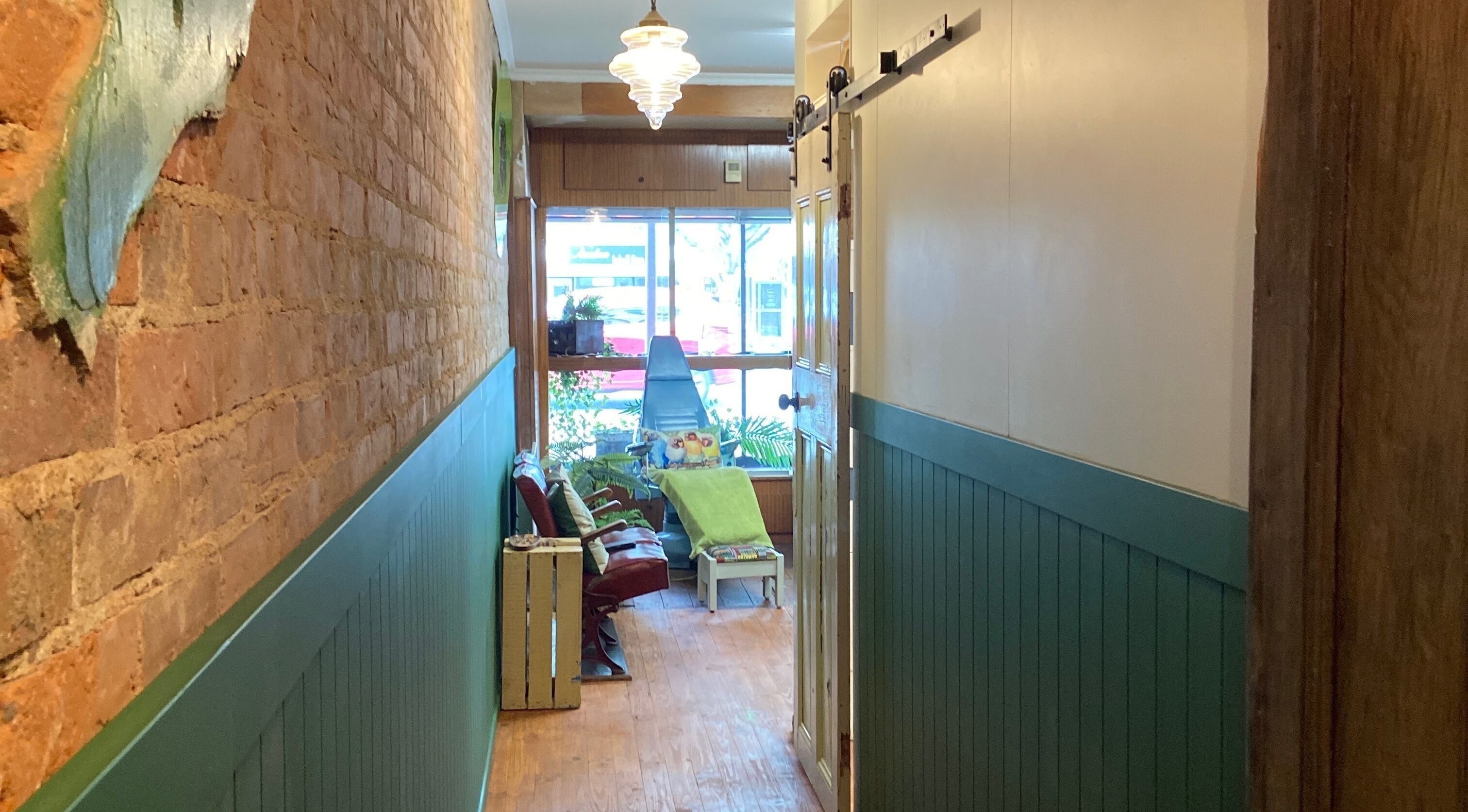 Inviting hallway at The Beauty Bach Invers, Invercargill, showcasing rustic brick and green panel walls.