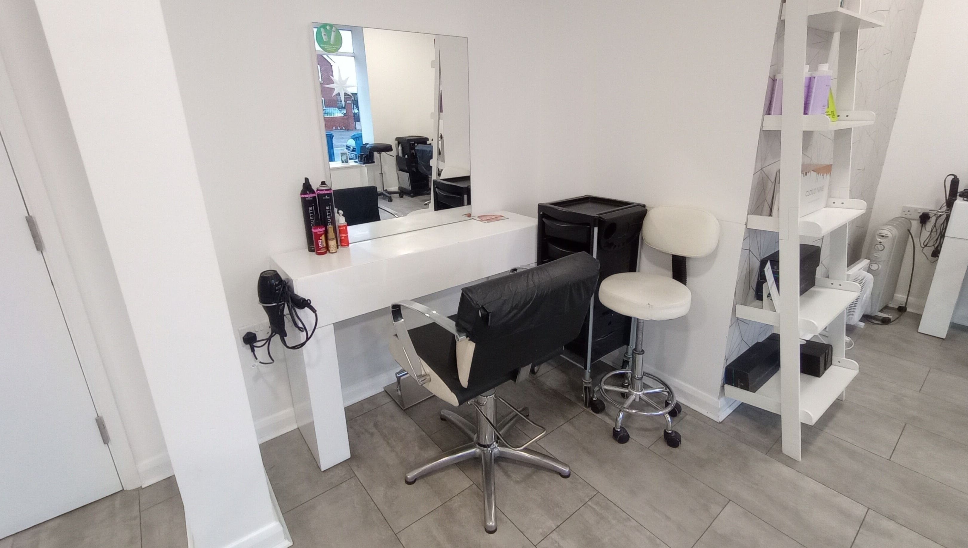 Modern salon setup at Emily H at Roots, Windsor, England, GB. Stylish mirror, chair, and products on display.