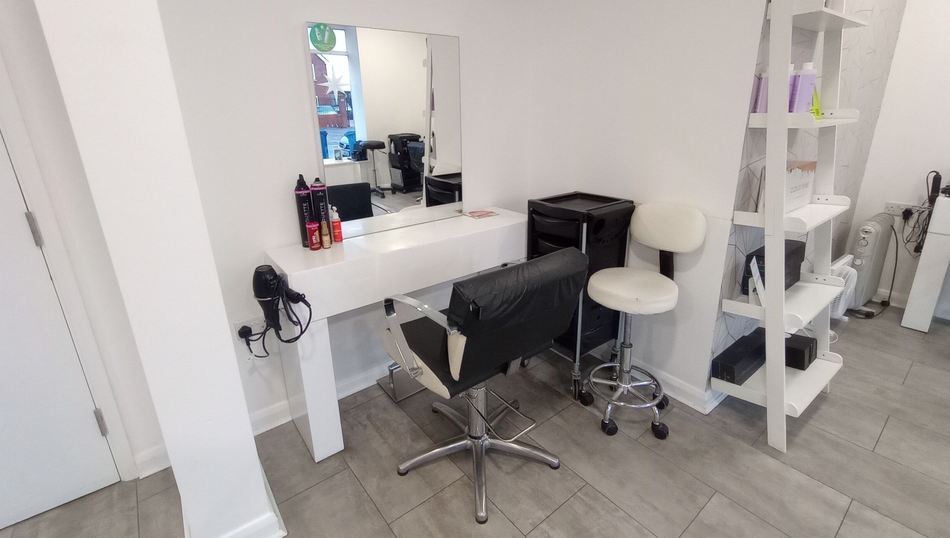 Modern salon setup at Emily H at Roots, Windsor, England, GB. Stylish mirror, chair, and products on display.