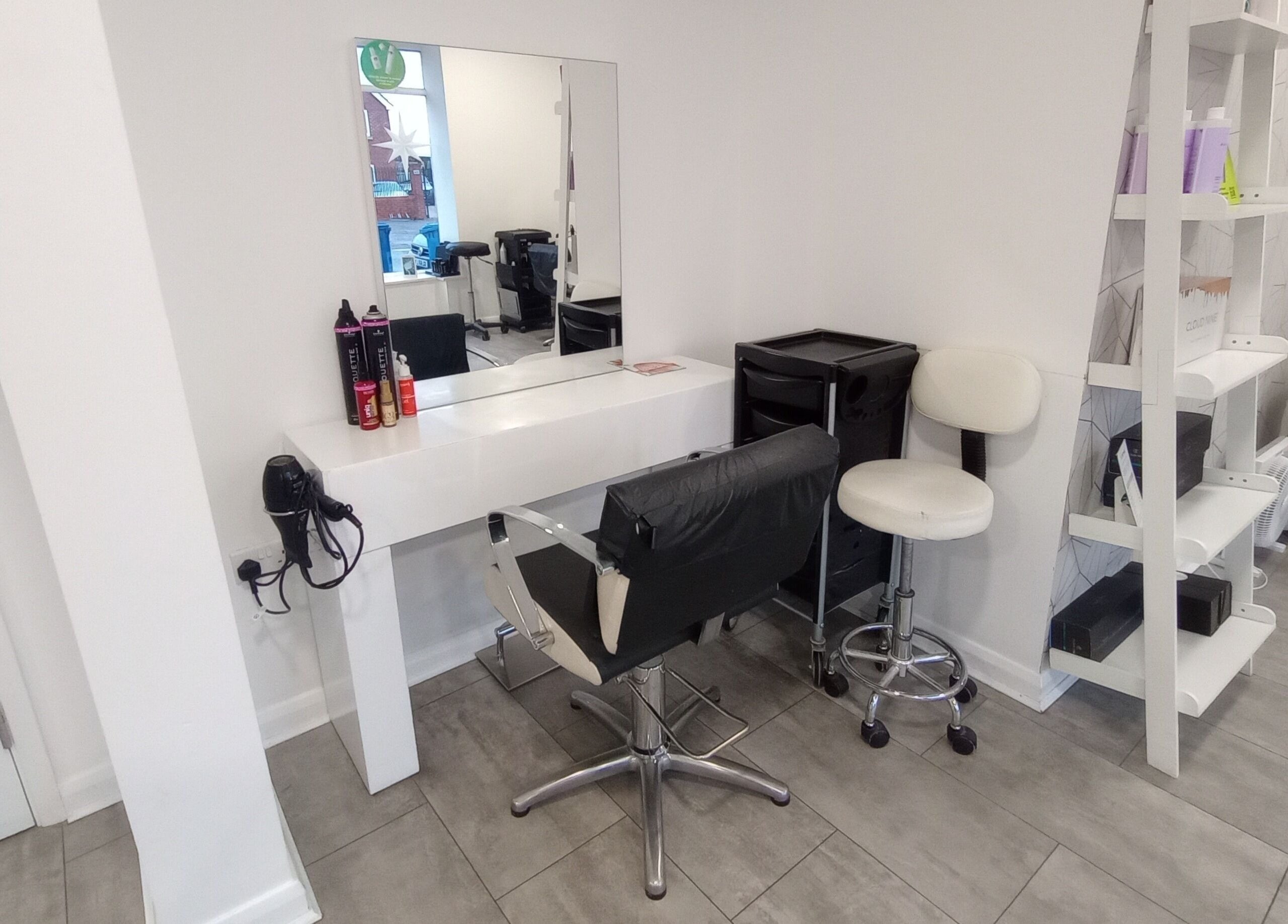 Modern salon setup at Emily H at Roots, Windsor, England, GB. Stylish mirror, chair, and products on display.