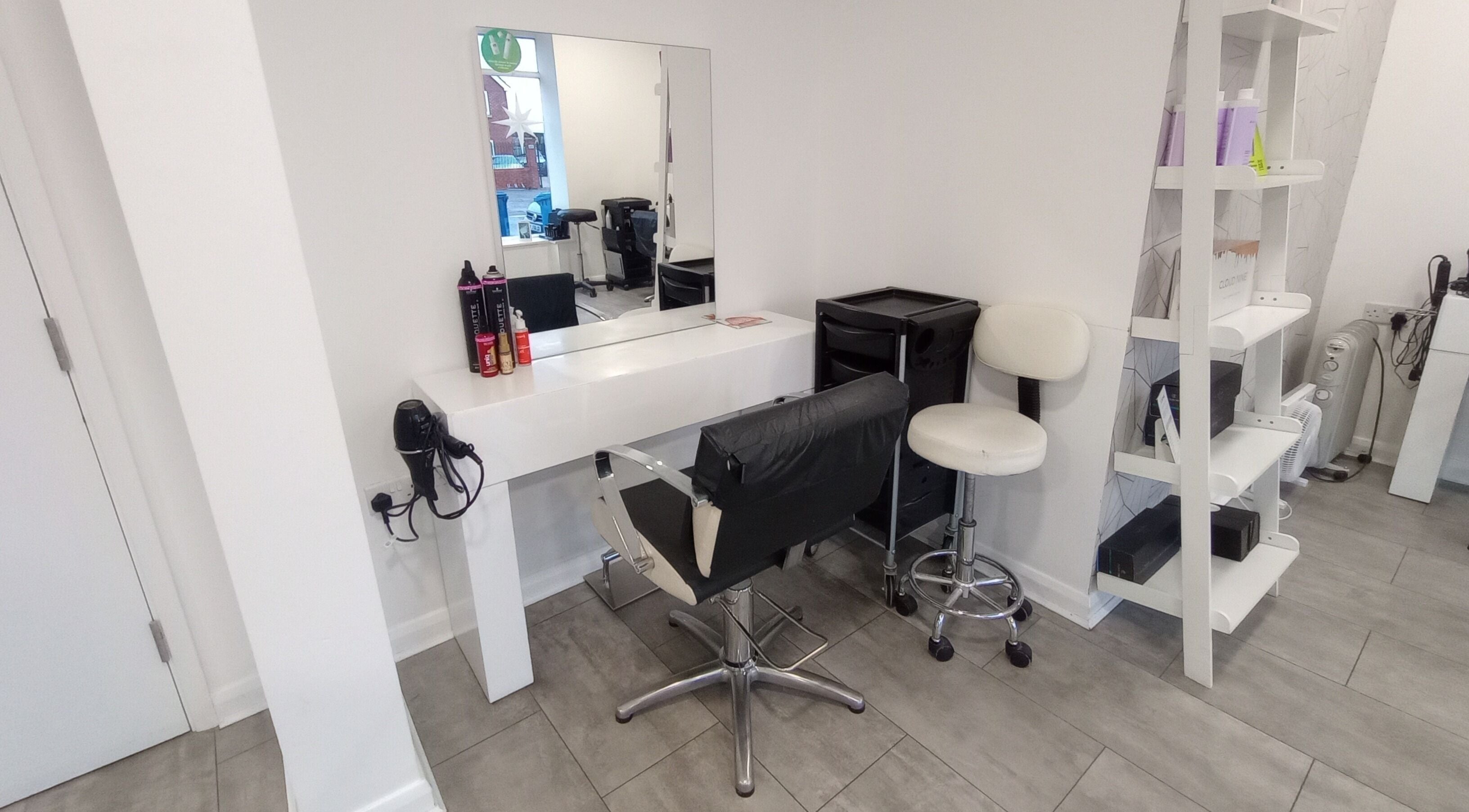 Modern salon setup at Emily H at Roots, Windsor, England, GB. Stylish mirror, chair, and products on display.