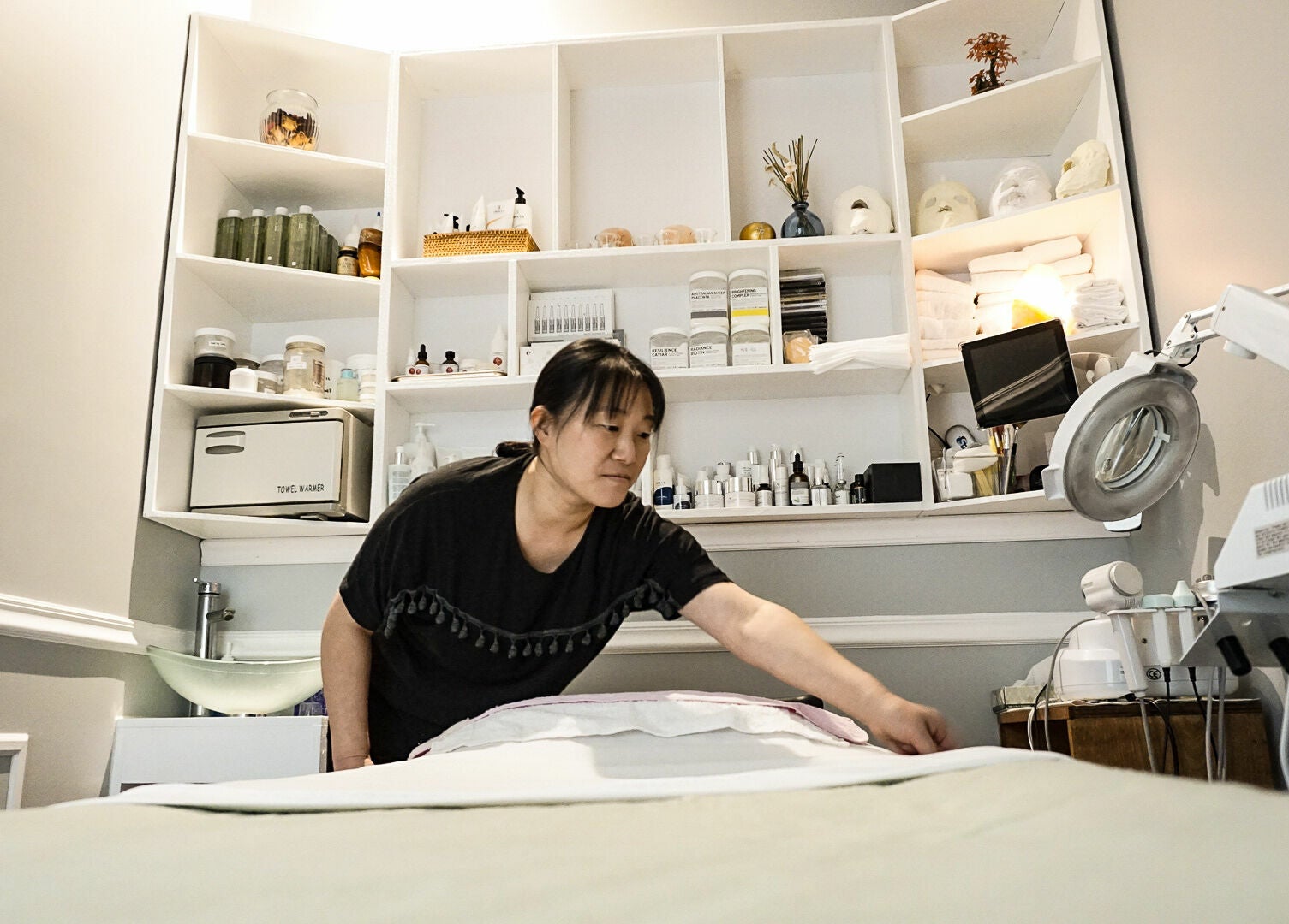 Aesthetician prepares spa bed at Pure Green Locust Valley, Locust Valley, New York, US.