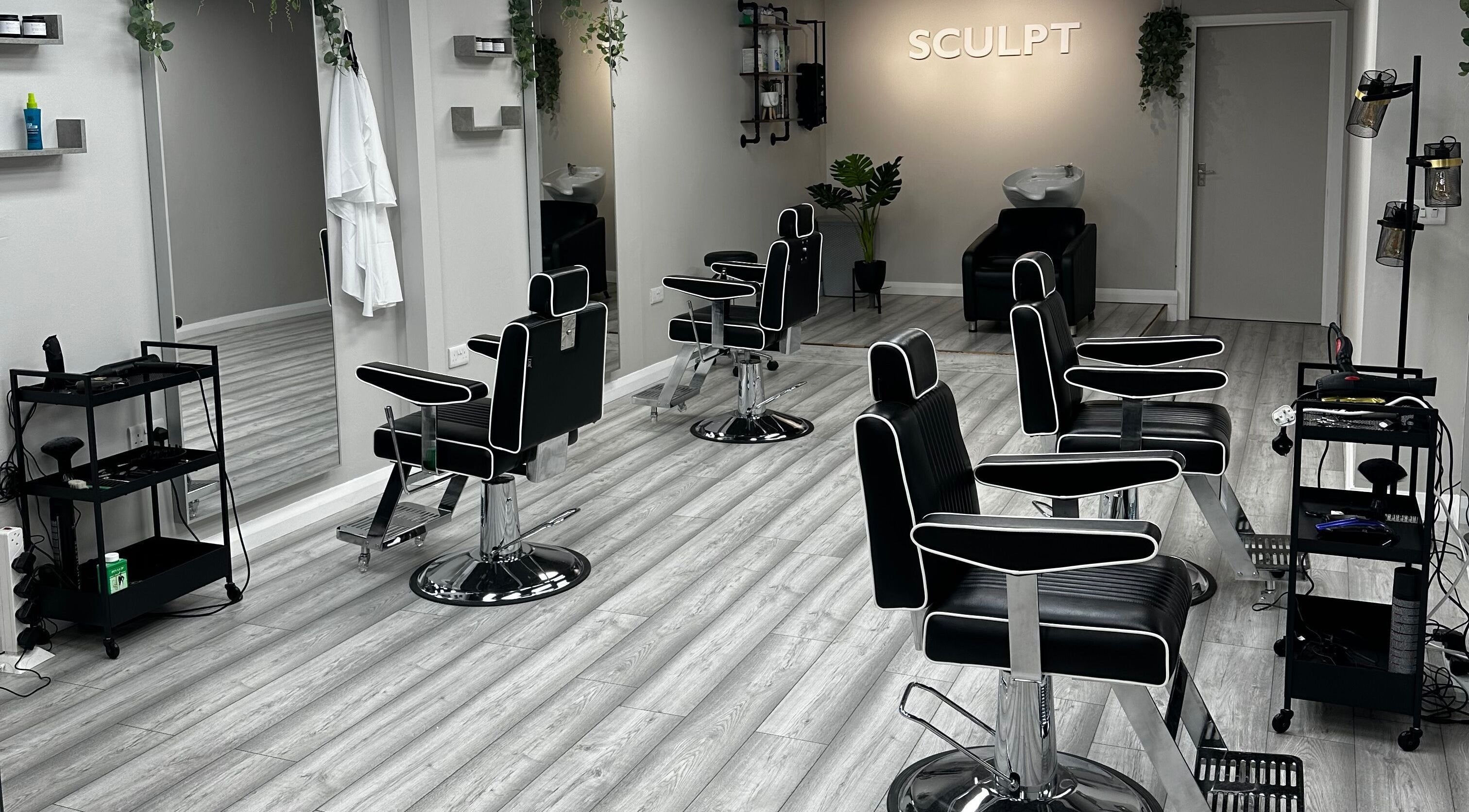 Modern interior of Sculpt salon in Newry, Northern Ireland, GB featuring sleek black chairs and mirrors.
