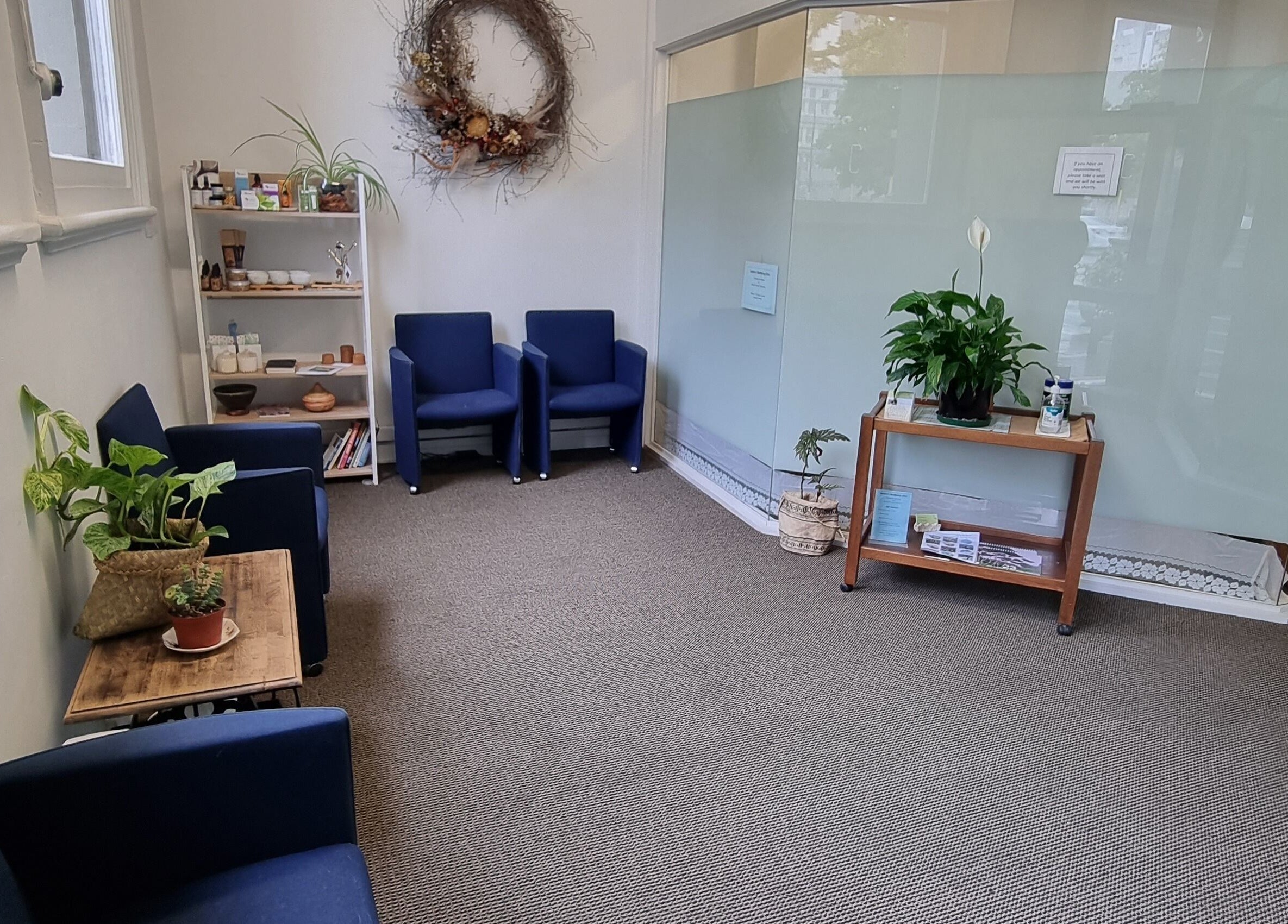 Cozy lounge at Self Mind & Body in Dunedin, Otago, NZ featuring blue chairs and lush plants.