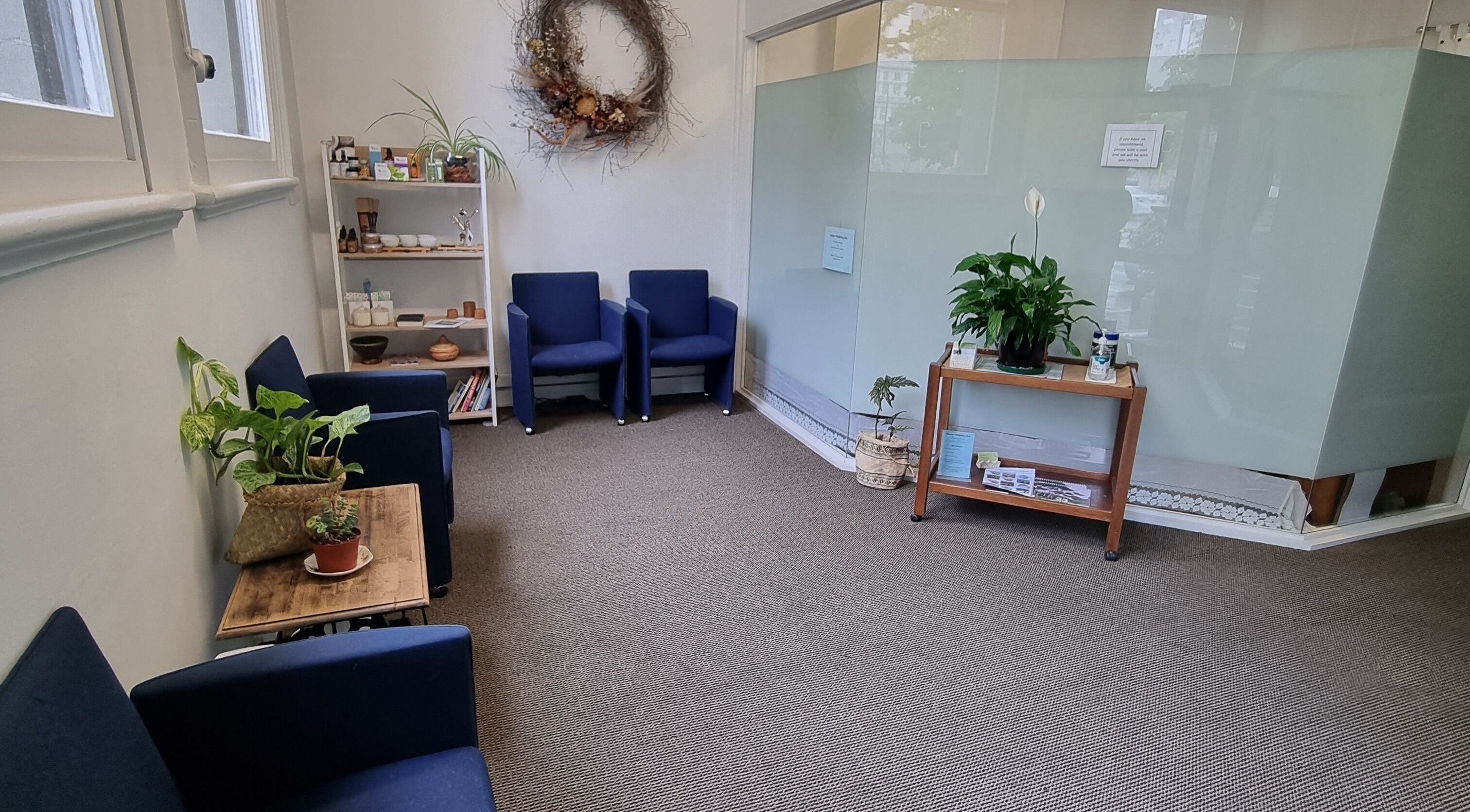 Cozy lounge at Self Mind & Body in Dunedin, Otago, NZ featuring blue chairs and lush plants.