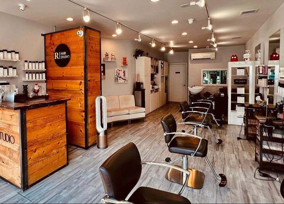 Interior of R Hair Studio, New York, New York, US, showcasing modern salon chairs and product displays.
