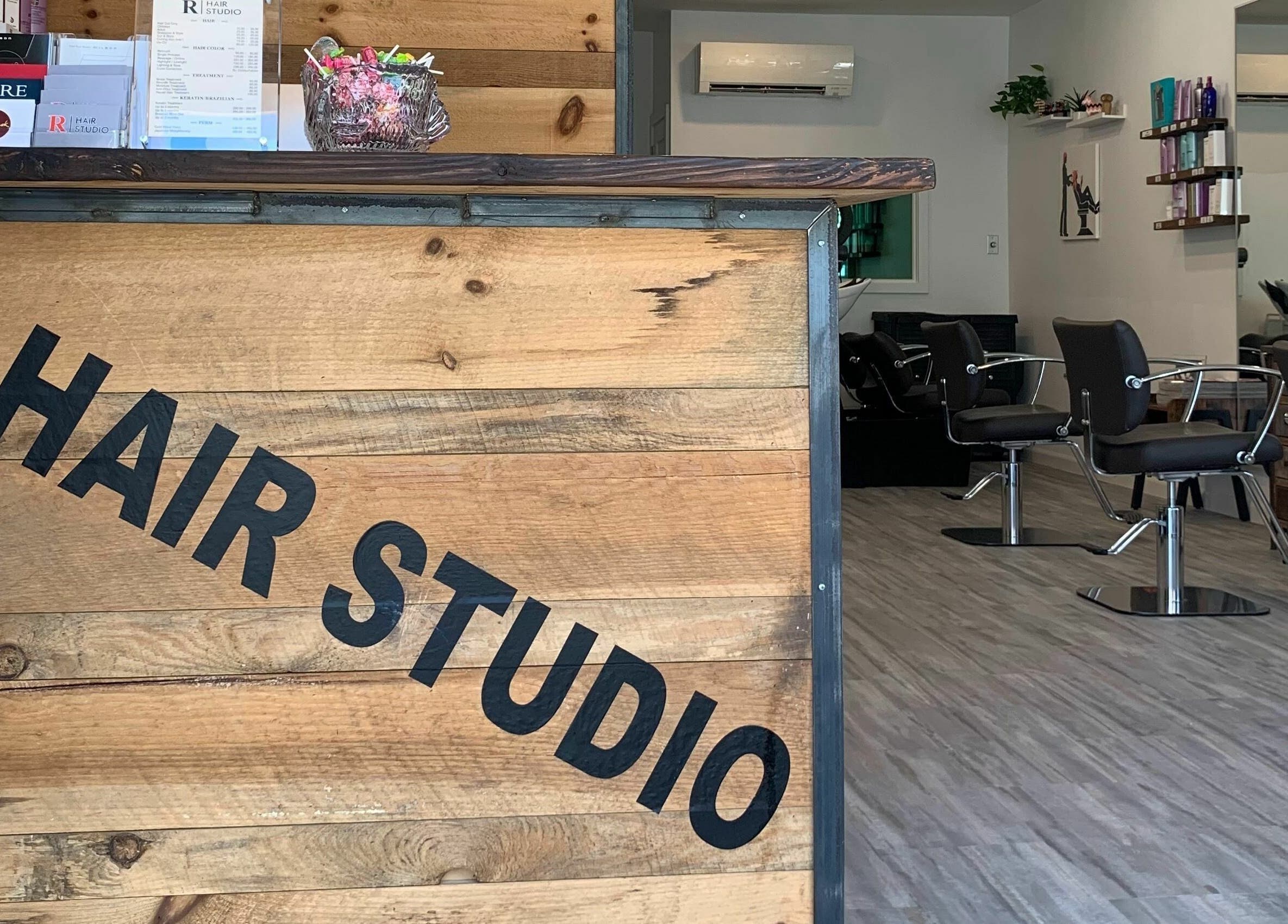 Inside R Hair Studio in New York, New York, US, showcasing stylish chairs and a rustic wooden reception.