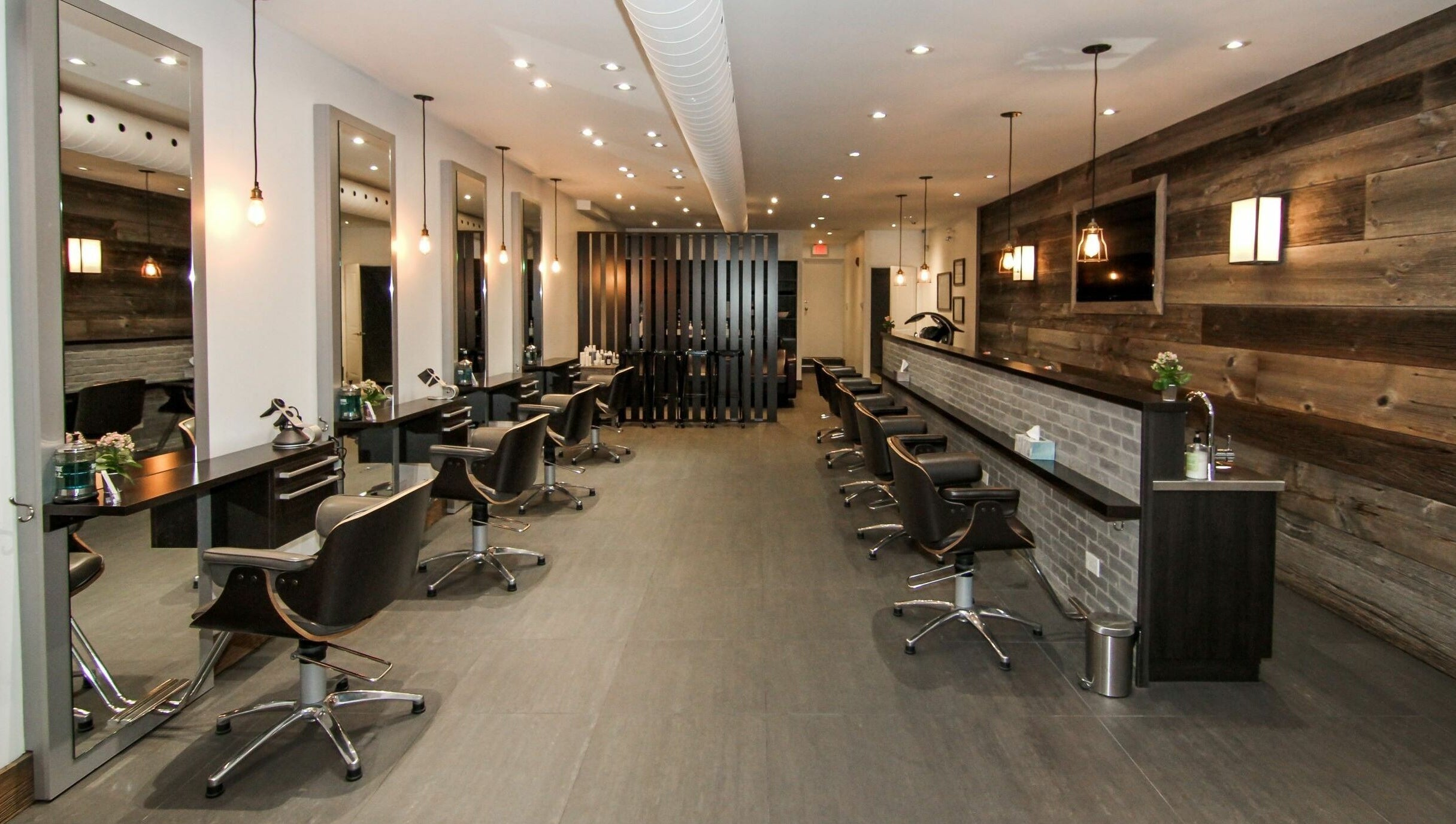 Elegant salon interior at Brixton Parlour, Toronto, CA, featuring modern styling stations and wood accents.