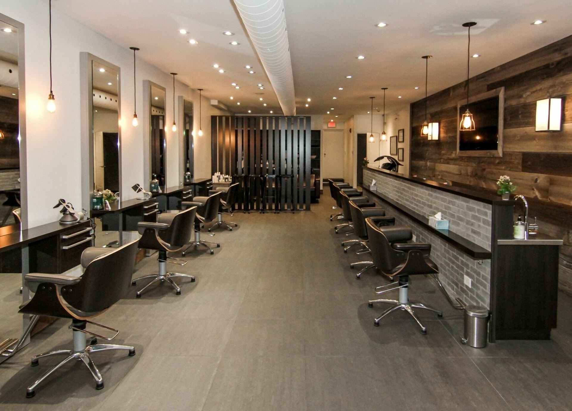Elegant salon interior at Brixton Parlour, Toronto, CA, featuring modern styling stations and wood accents.