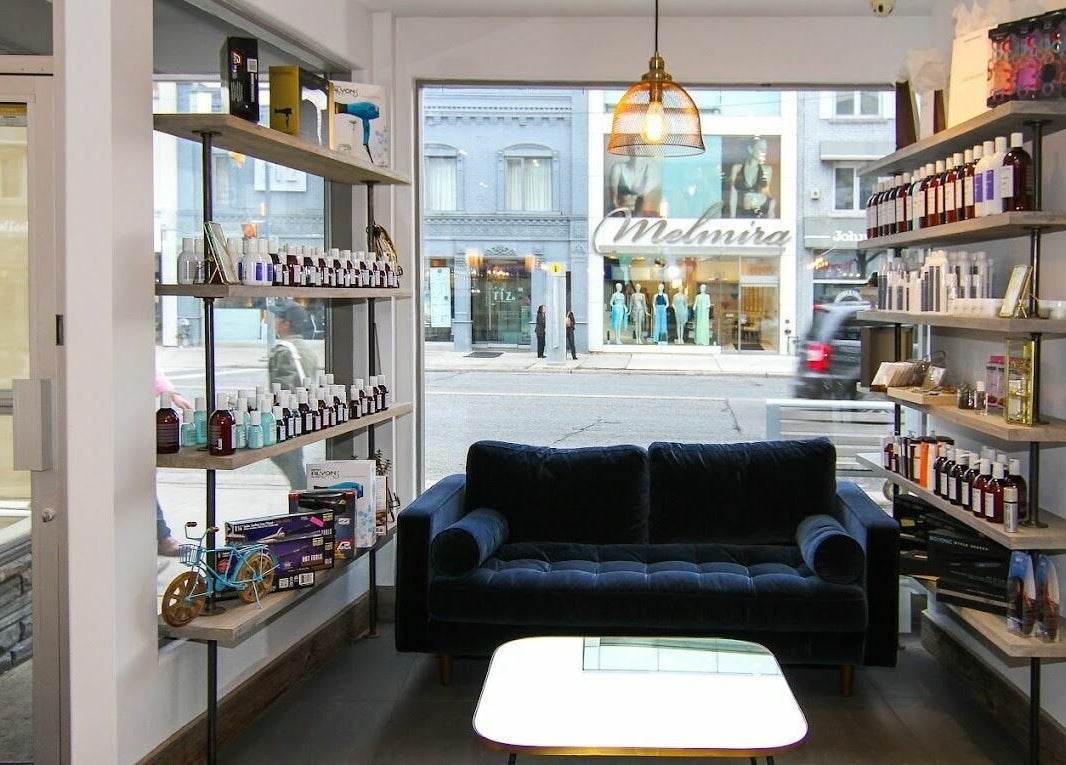 Bright, inviting Brixton Parlour interior in Toronto, CA with lush couch and product-filled shelves.