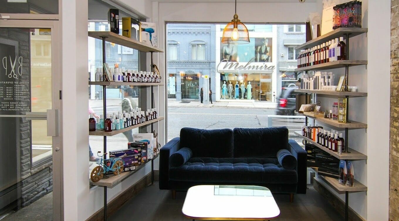 Bright, inviting Brixton Parlour interior in Toronto, CA with lush couch and product-filled shelves.