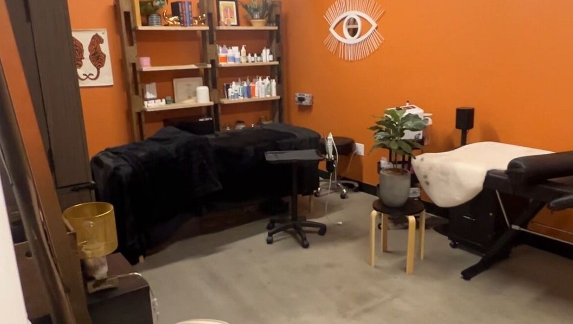 Warm, inviting treatment room at Lemon's Esthetics Studio in South Jordan, Utah, US with orange walls and plush beds.