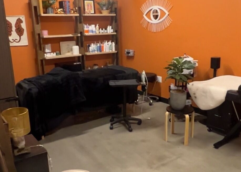 Warm, inviting treatment room at Lemon's Esthetics Studio in South Jordan, Utah, US with orange walls and plush beds.
