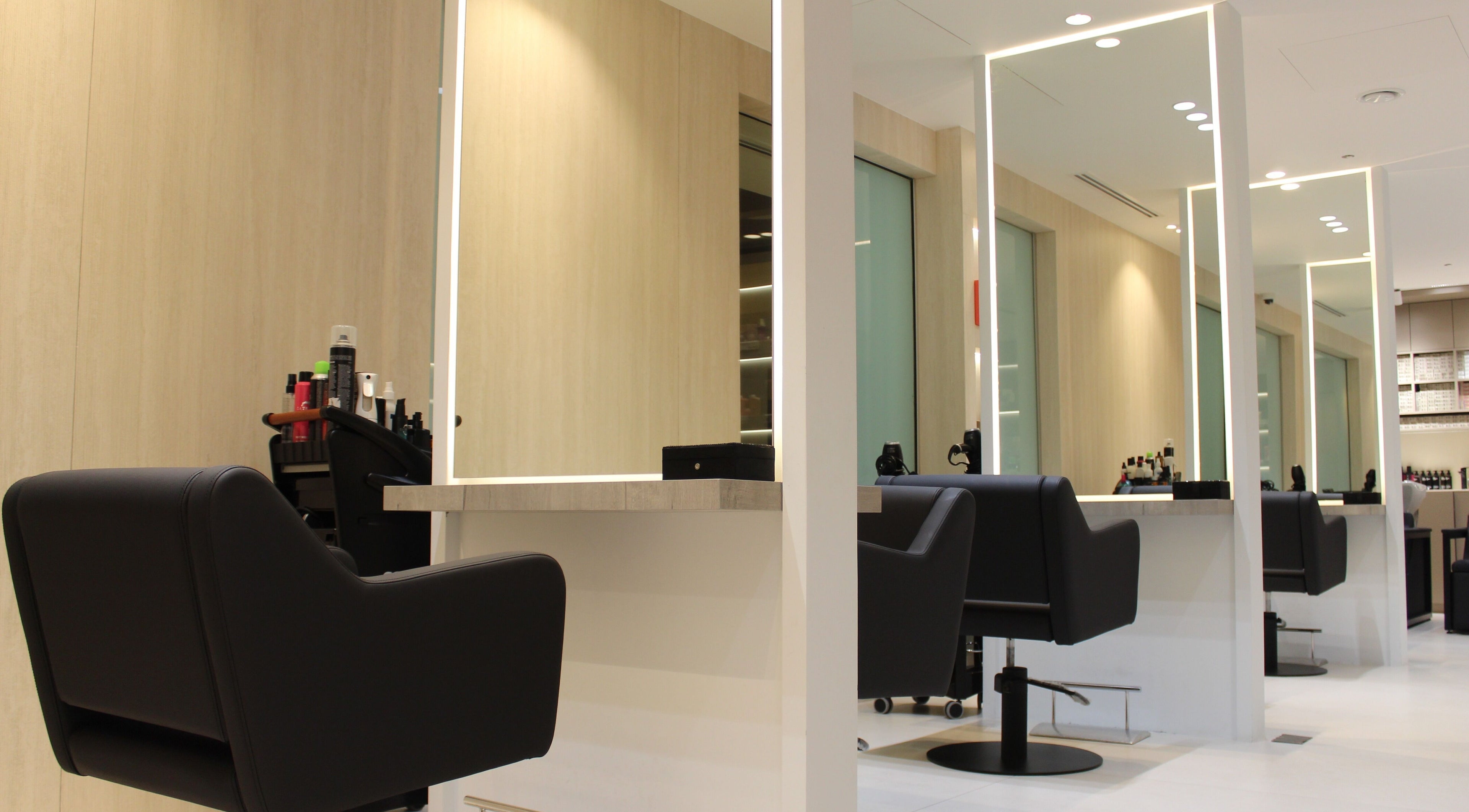 Chic and modern styling stations at Vita Lita Beauty Salon, Dubai, AE, showcasing sleek black chairs.