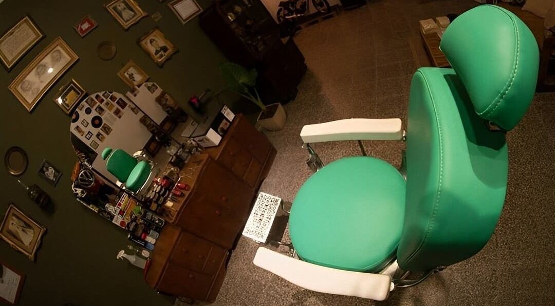 Silla verde en Barberia Dandy, Cañada De Gomez, Santa Fe, AR, decorada con fotos vintage.