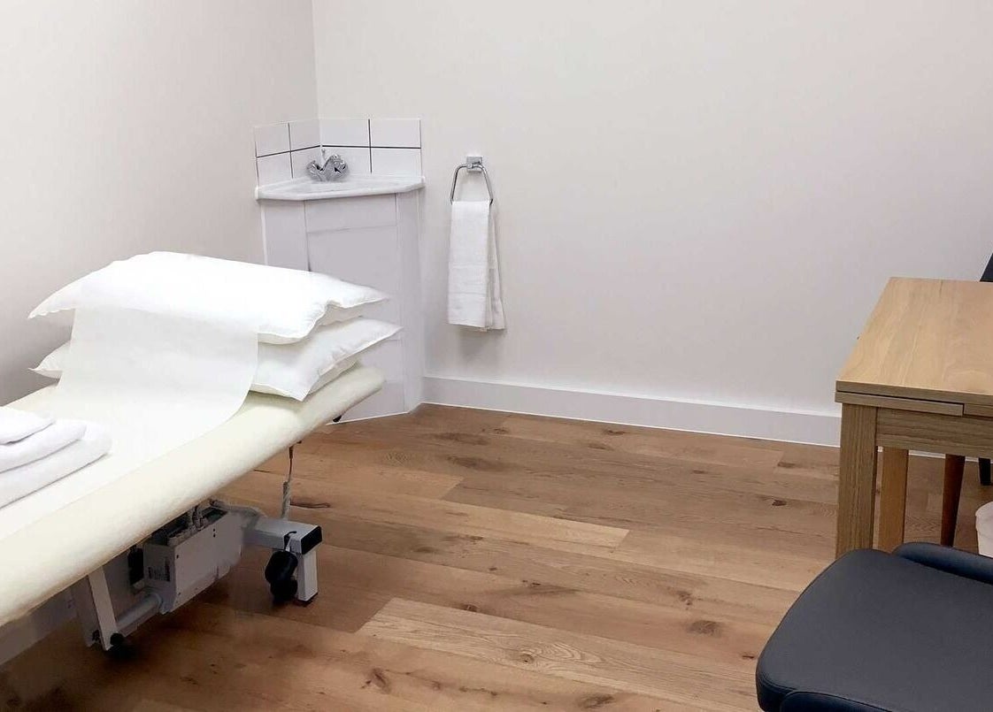 Cozy treatment room at Danugur Monument, London, England, GB featuring a massage table and wooden furnishings.