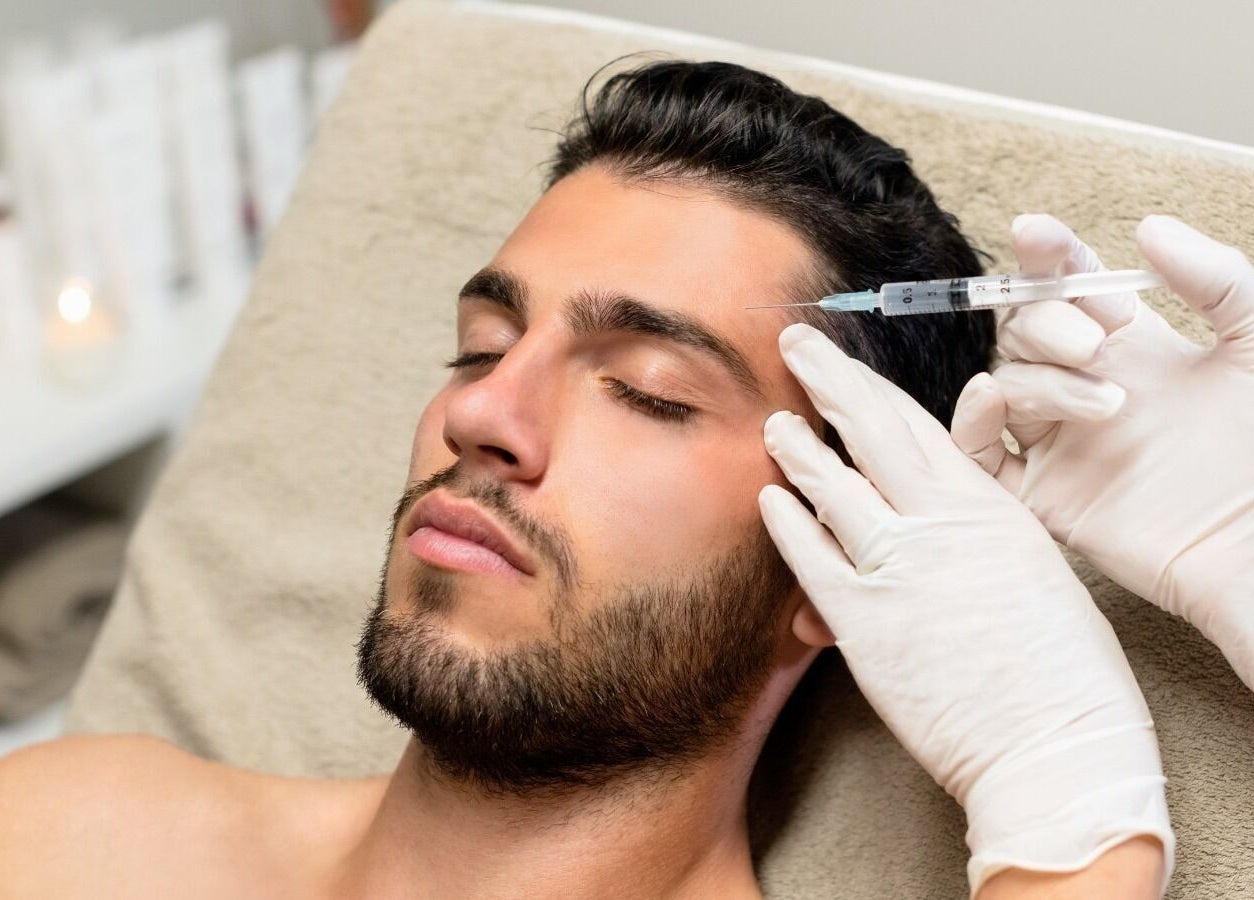 Man receiving beauty treatment at Danugur Monument in London, England, GB, promoting relaxation and care.