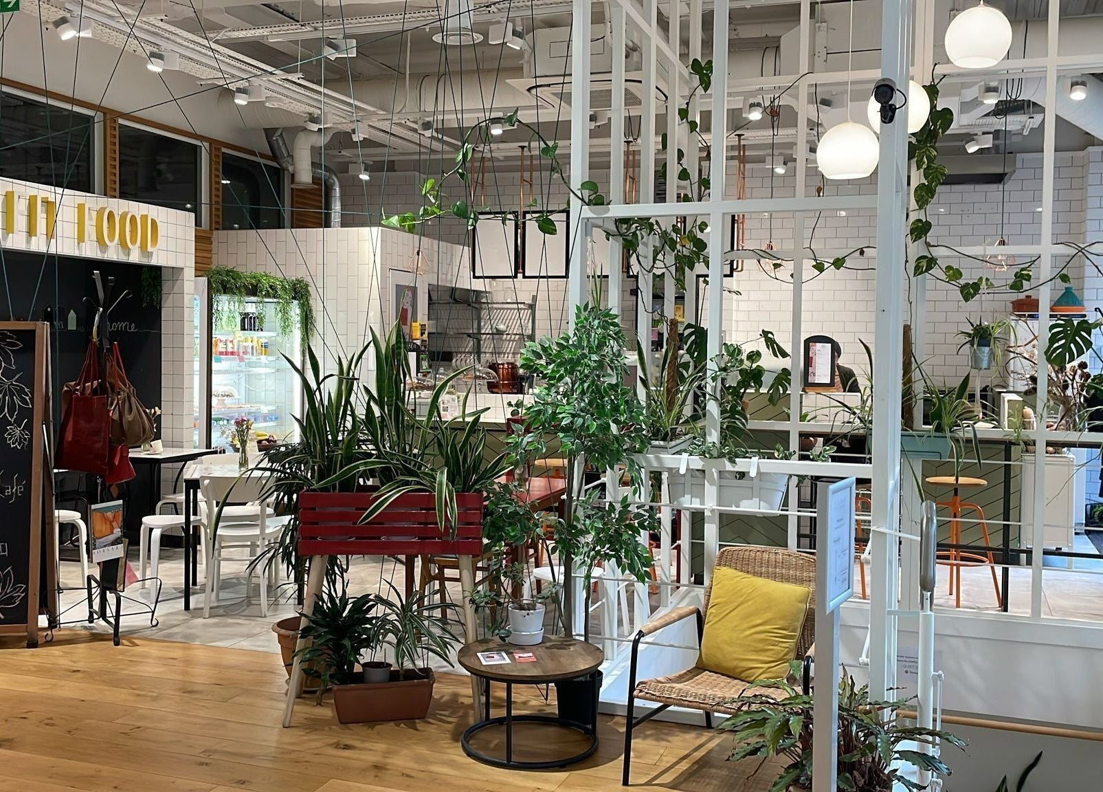 Relaxing cafe interior with lush plants at Maen (Men) Monument, London, England, GB.