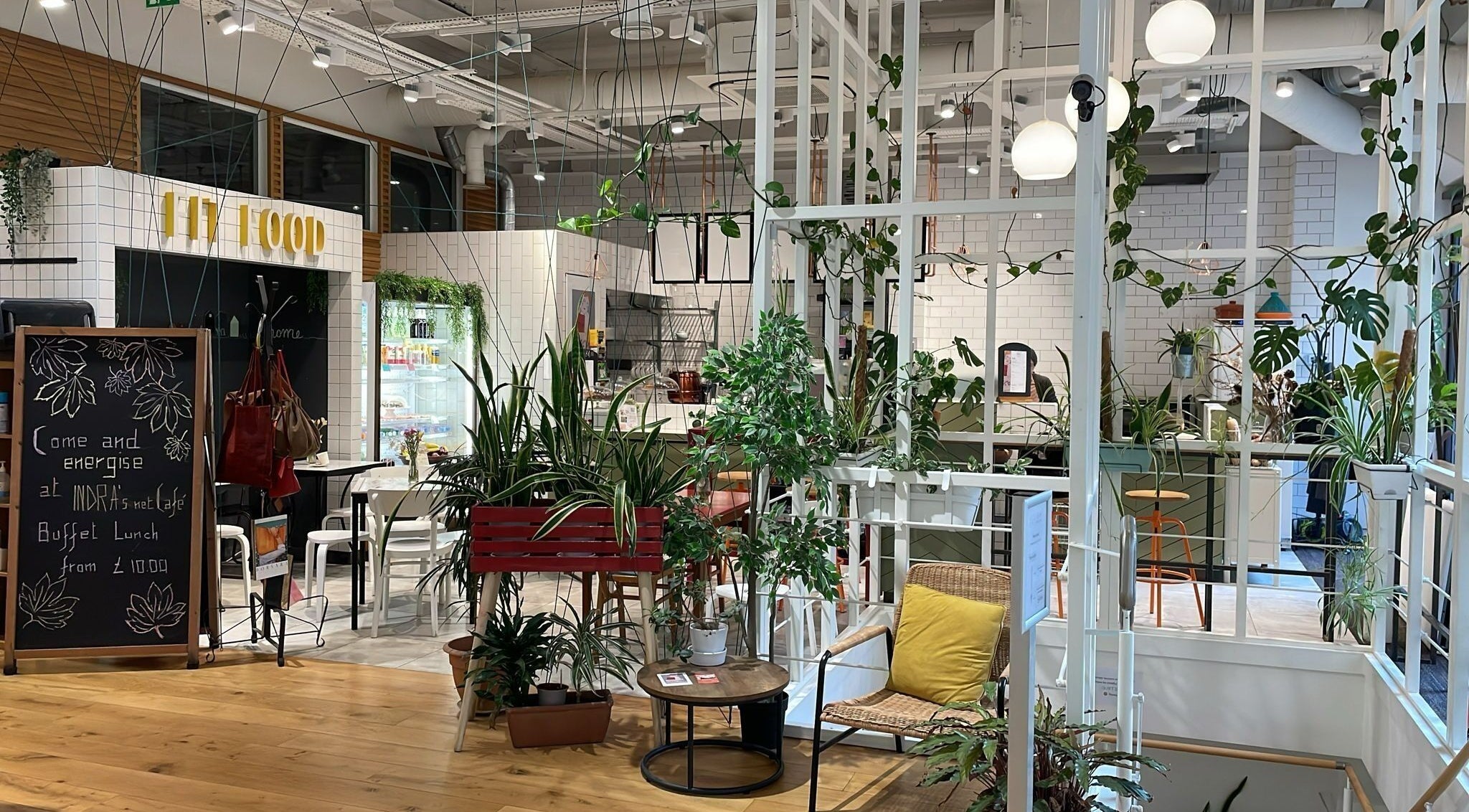 Relaxing cafe interior with lush plants at Maen (Men) Monument, London, England, GB.