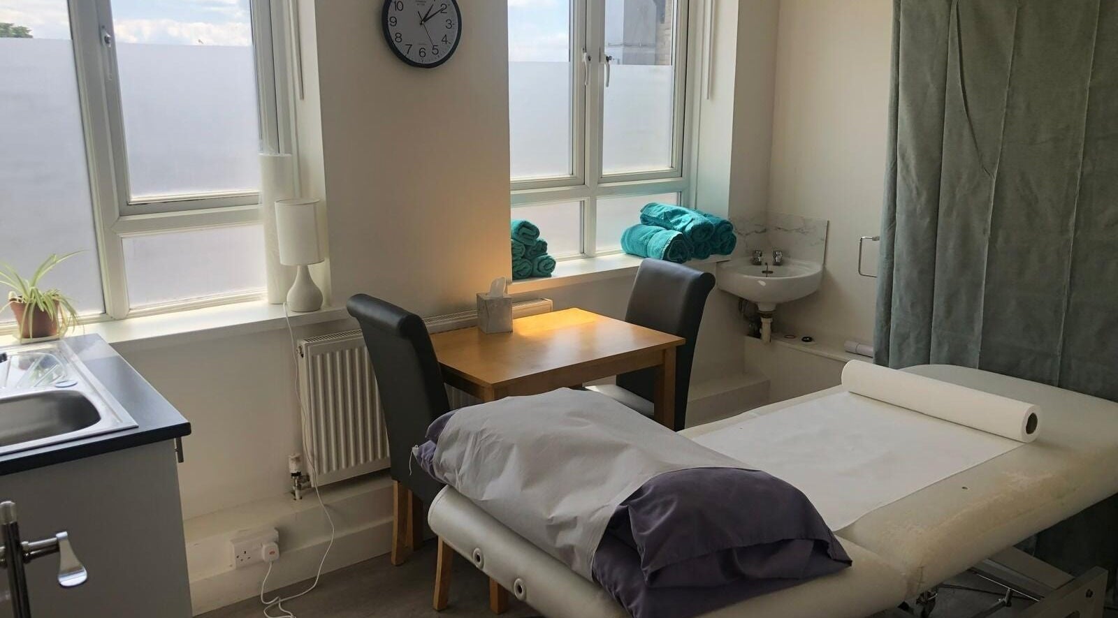 A soothing treatment room at Maen (Men) London Clapham in London, England, GB with massage table and towels.