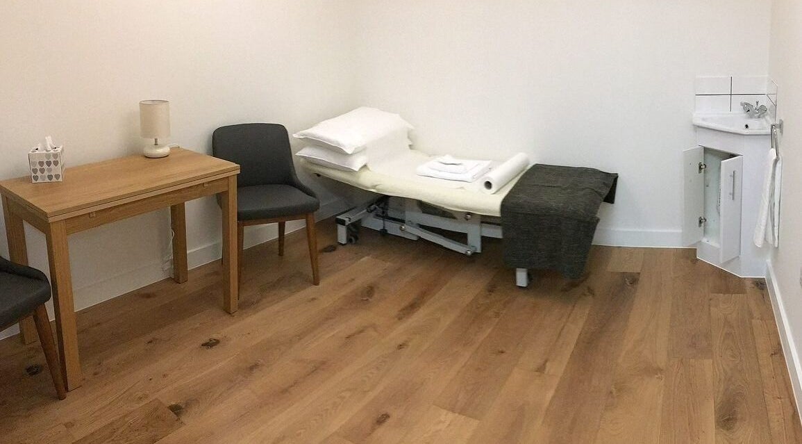 Peaceful therapy room at Maen Men Monument, London, England, GB with a treatment bed and chairs.