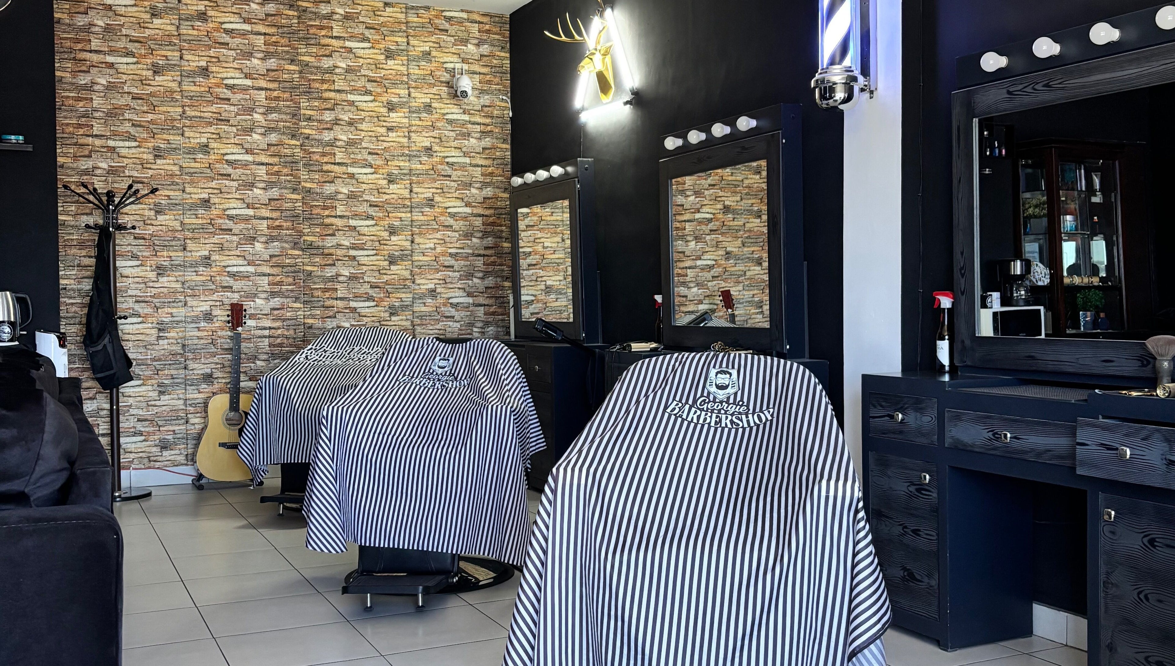 Sillas de Georgie Barbershop en Hermosillo, Sonora, MX con decoración moderna y capas con logo.