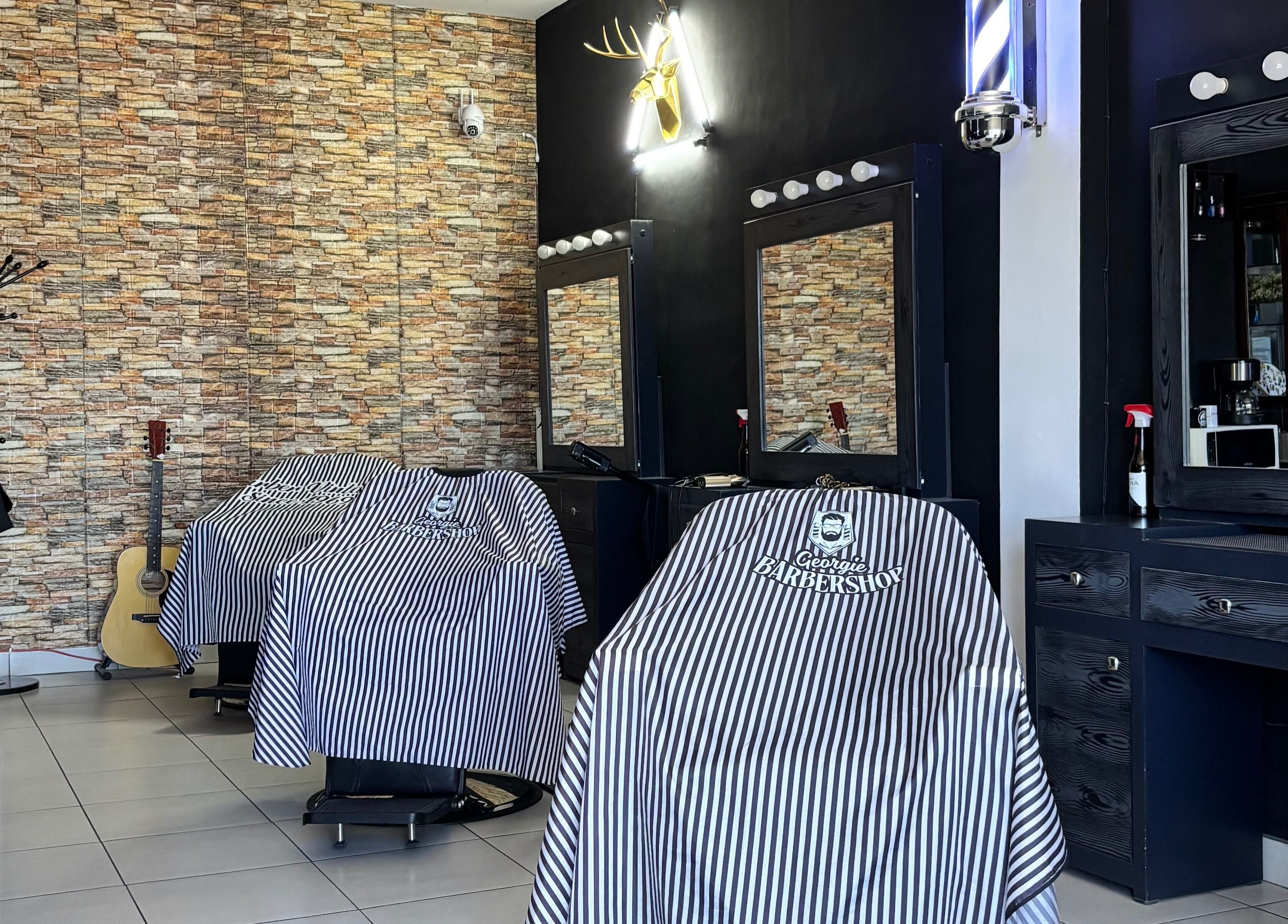 Sillas de Georgie Barbershop en Hermosillo, Sonora, MX con decoración moderna y capas con logo.