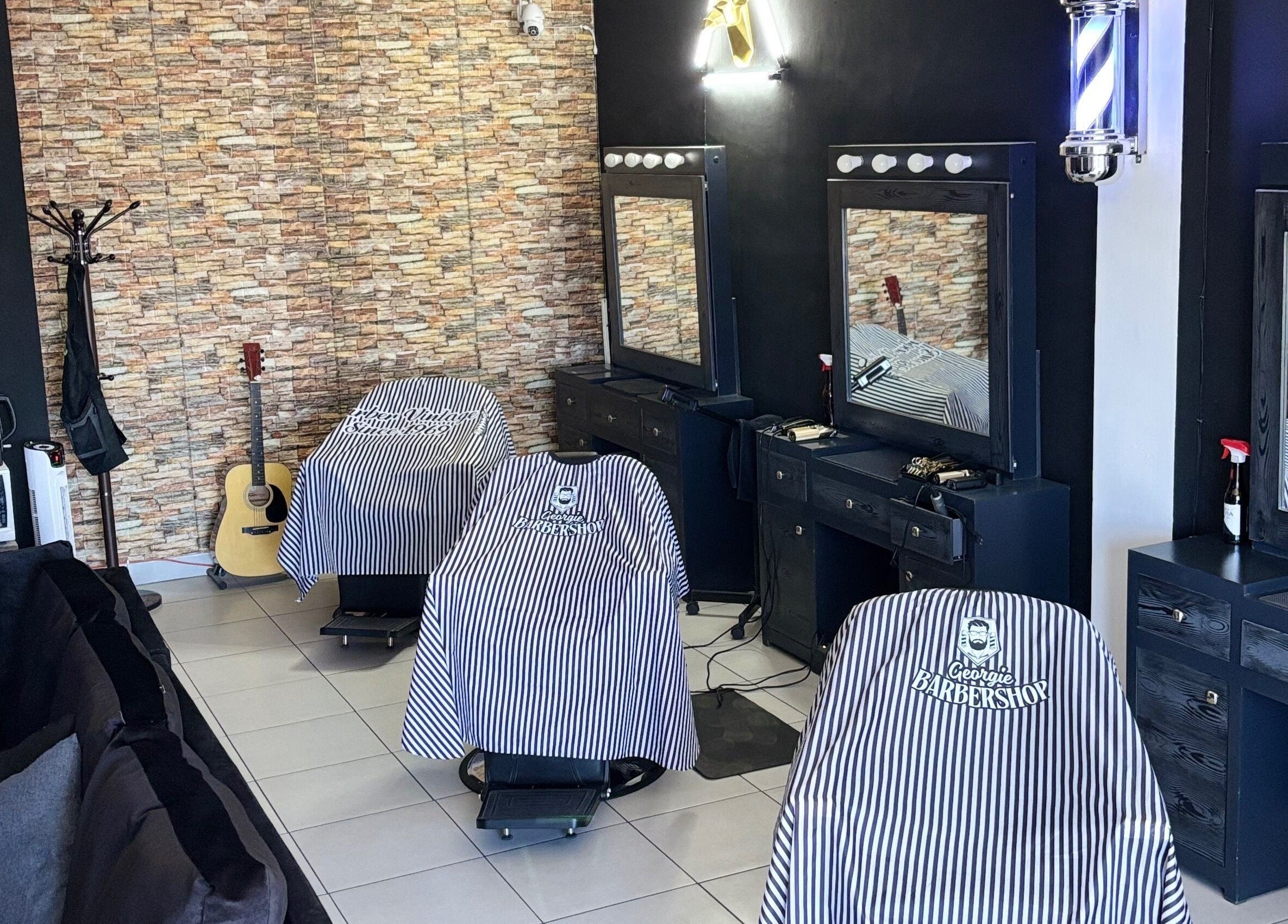 Interior de Georgie Barbershop en Hermosillo, Sonora, MX con sillas y espejos elegantes.