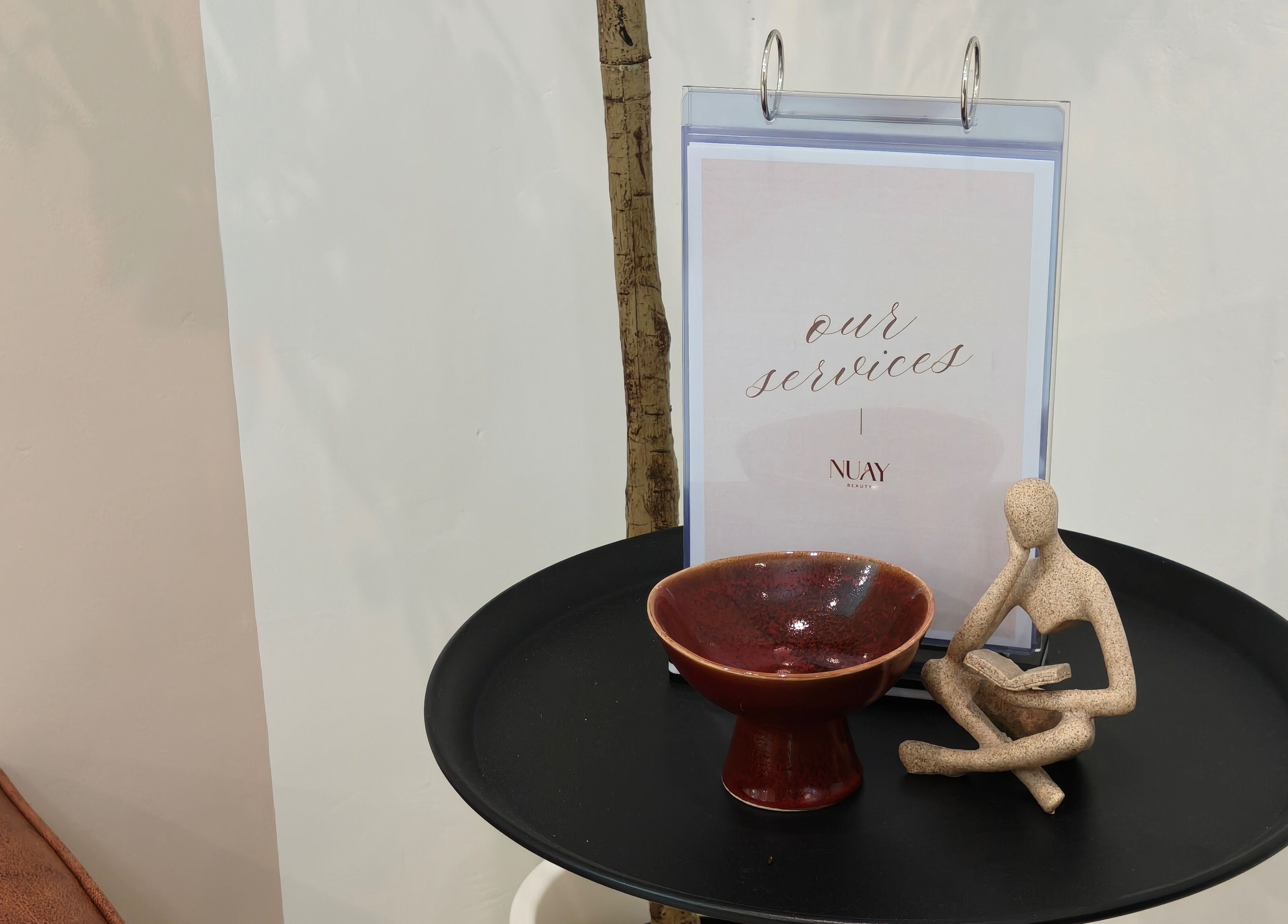 Nuay Beauty's service menu with decor in Shah Alam, Selangor, MY, featuring a clay bowl and figurine.
