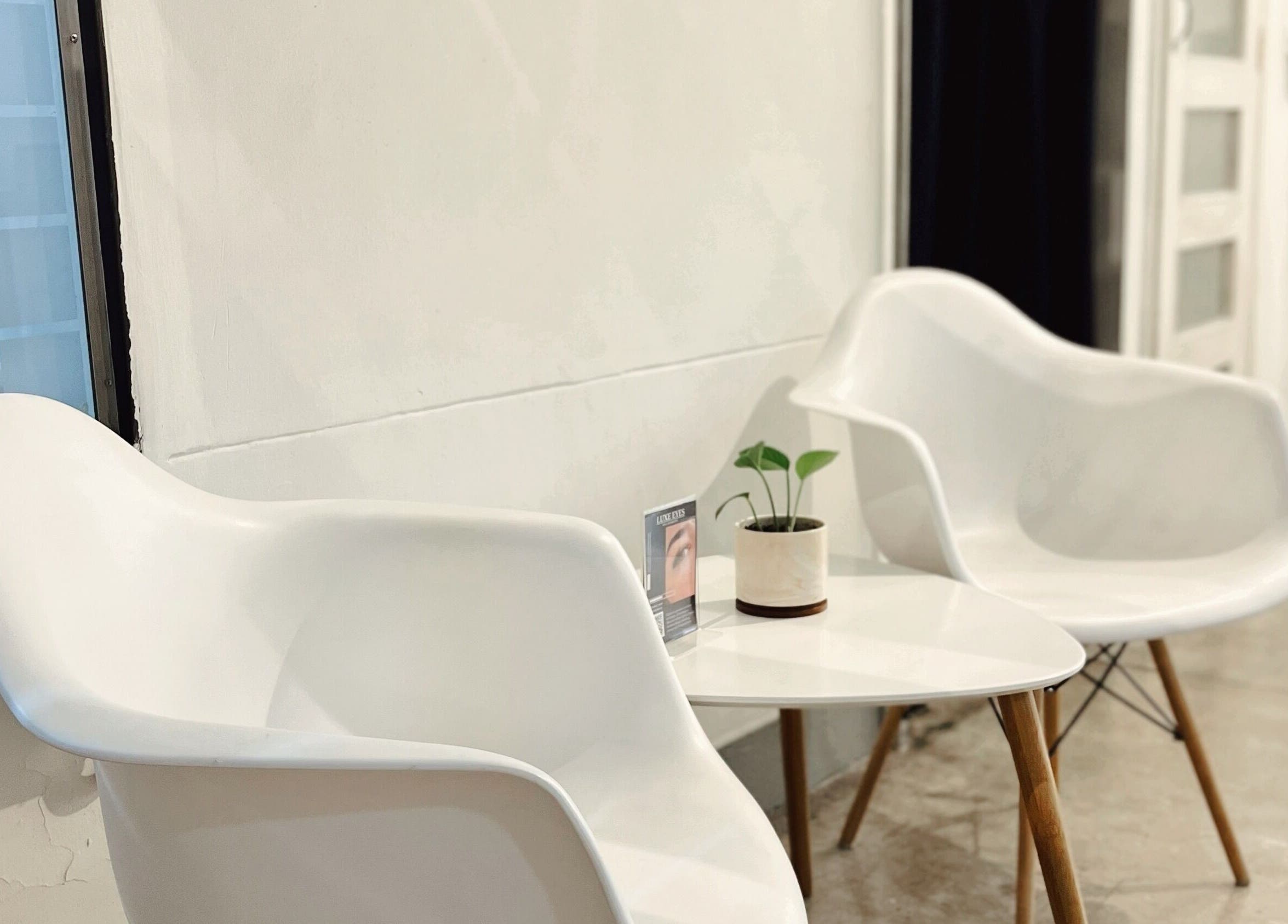 Cozy seating area at Luxe Eyes, Medellín, Antioquia, CO, featuring modern white chairs and a minimalist table.