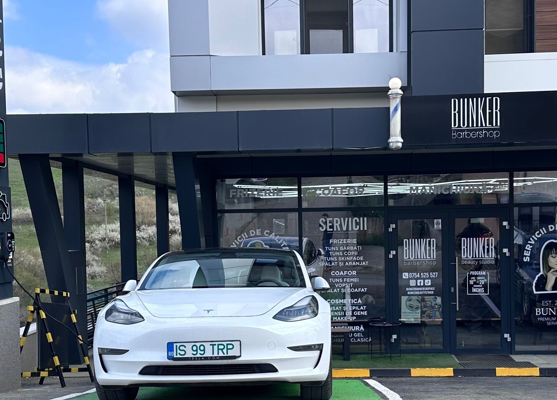 Intrarea principală Bunker Barbershop & Salon Iași, Județul Iași, RO, cu mașină electrică parcată în față.