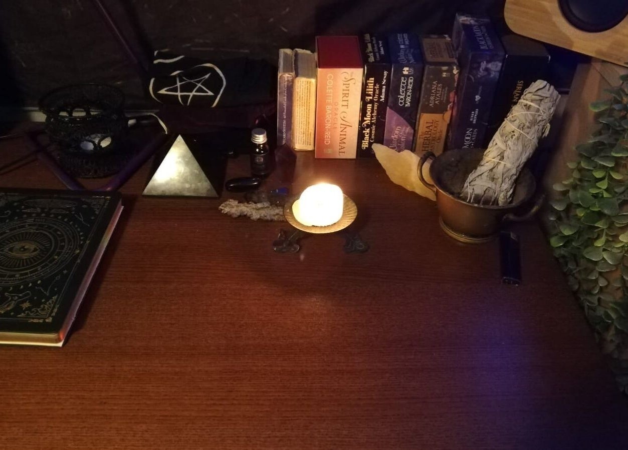 Candlelit wellness altar with books and sage at Violet Moon, Westcroft, England, GB.
