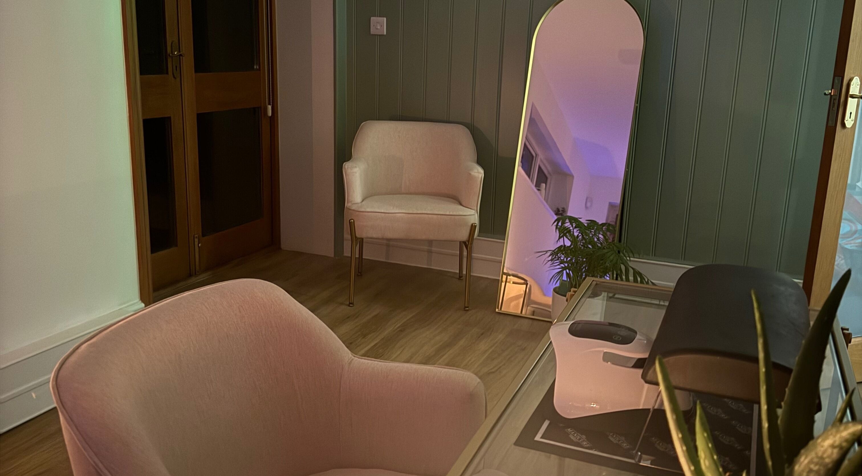 Cozy seating area at Beauty by Elliemai, Rowlands Castle, England, GB with modern chairs and mirror.
