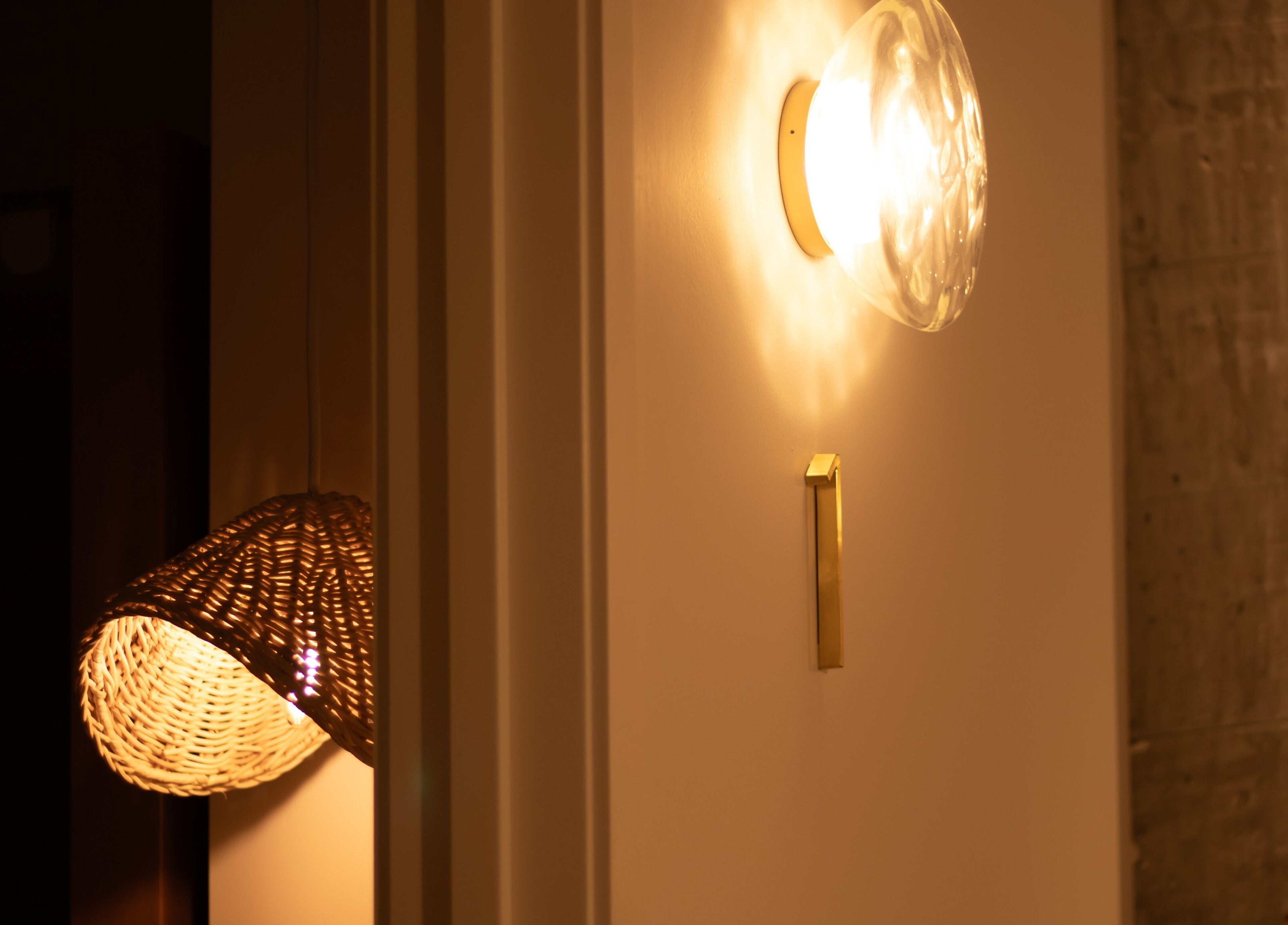 Elegant lighting at Studio Sweat in Auckland, NZ, featuring a woven basket lamp and wall sconce.