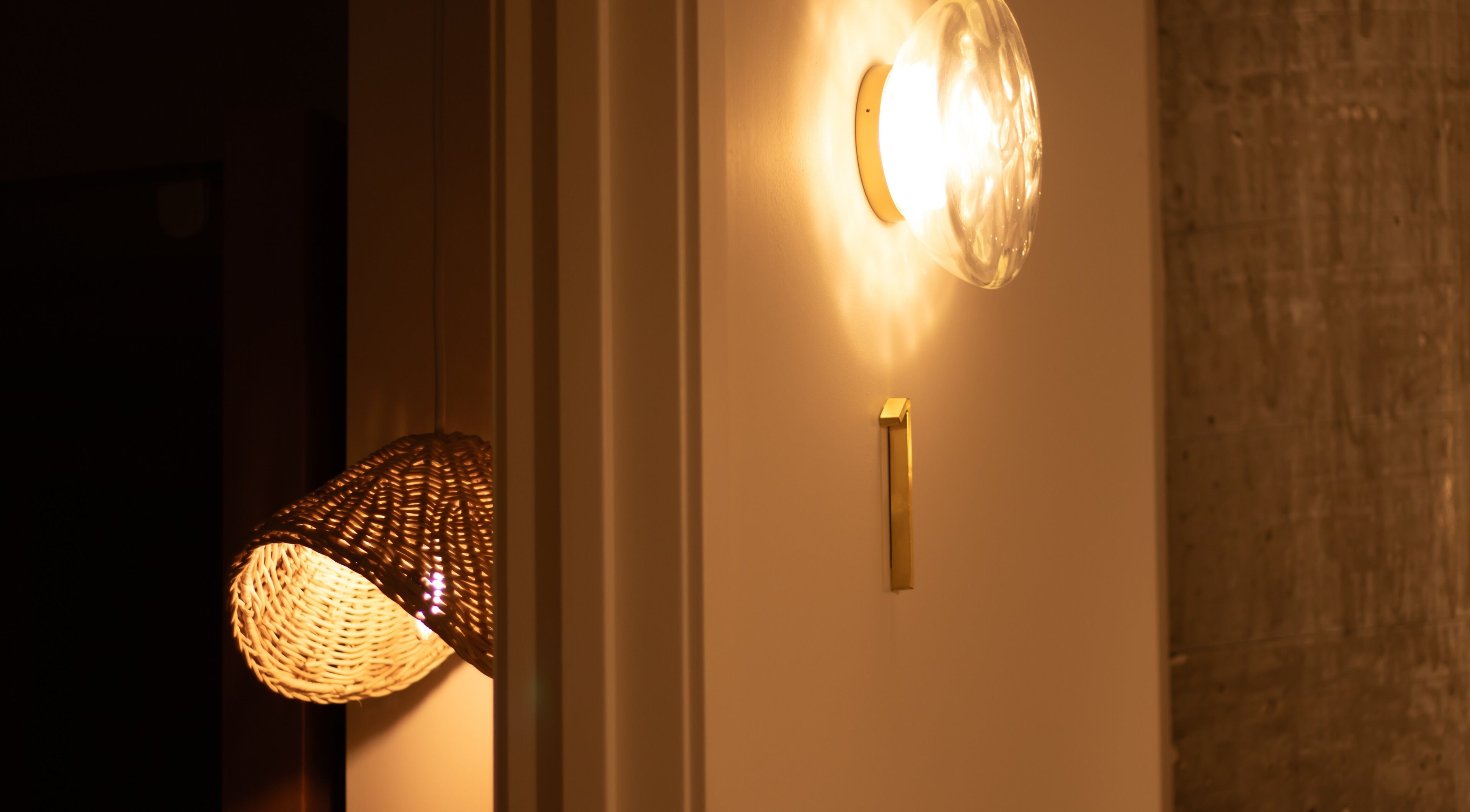 Elegant lighting at Studio Sweat in Auckland, NZ, featuring a woven basket lamp and wall sconce.