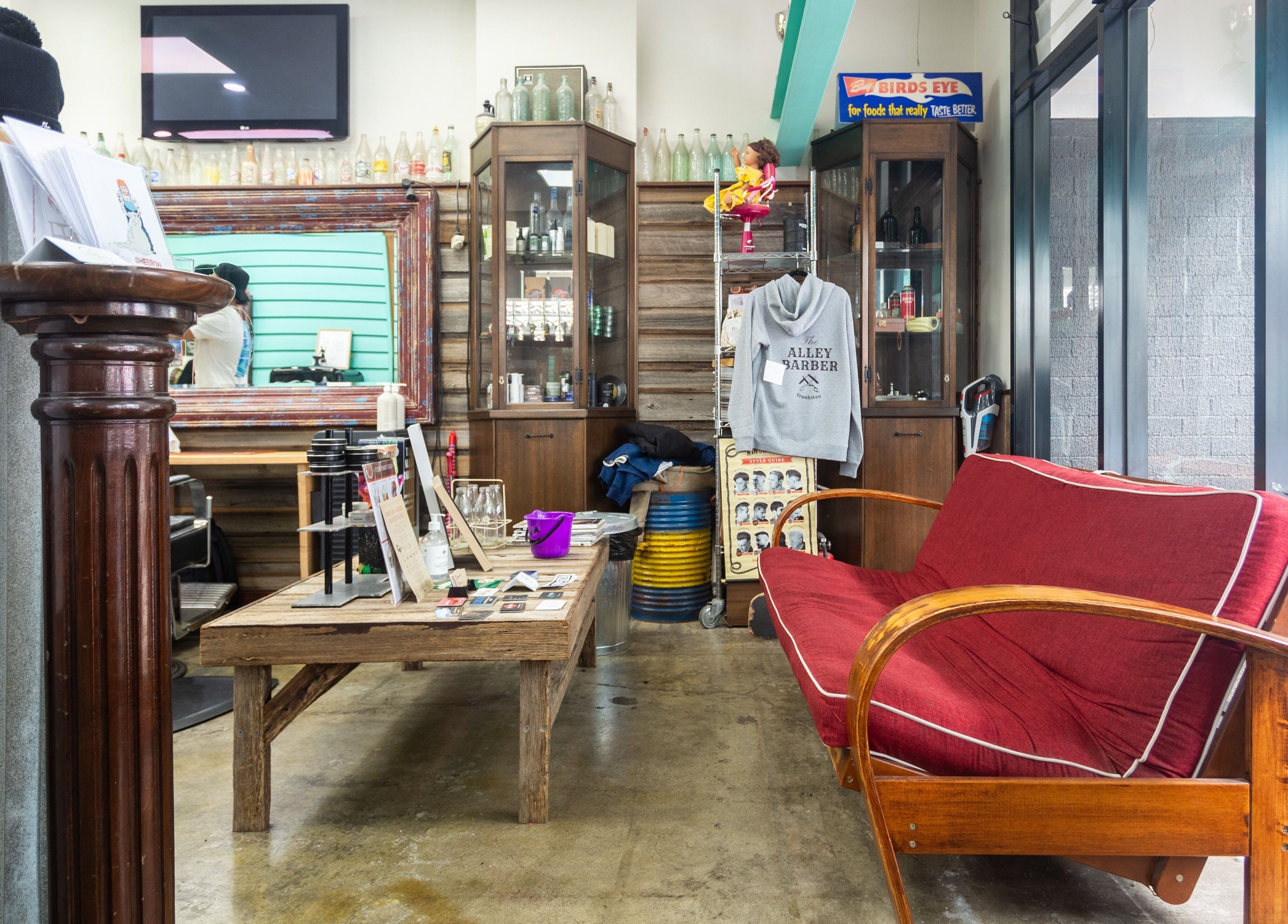 Inviting interior of The Alley Barber Frankston, featuring a red couch and vintage decor in Frankston, VIC, AU.