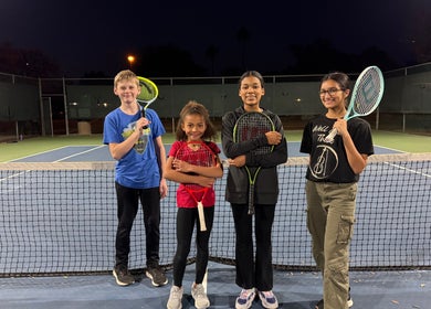 Kids with tennis rackets on a night court at Racket & Paddle Club, Gilbert, Arizona, US.