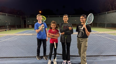 Kids with tennis rackets on a night court at Racket & Paddle Club, Gilbert, Arizona, US.