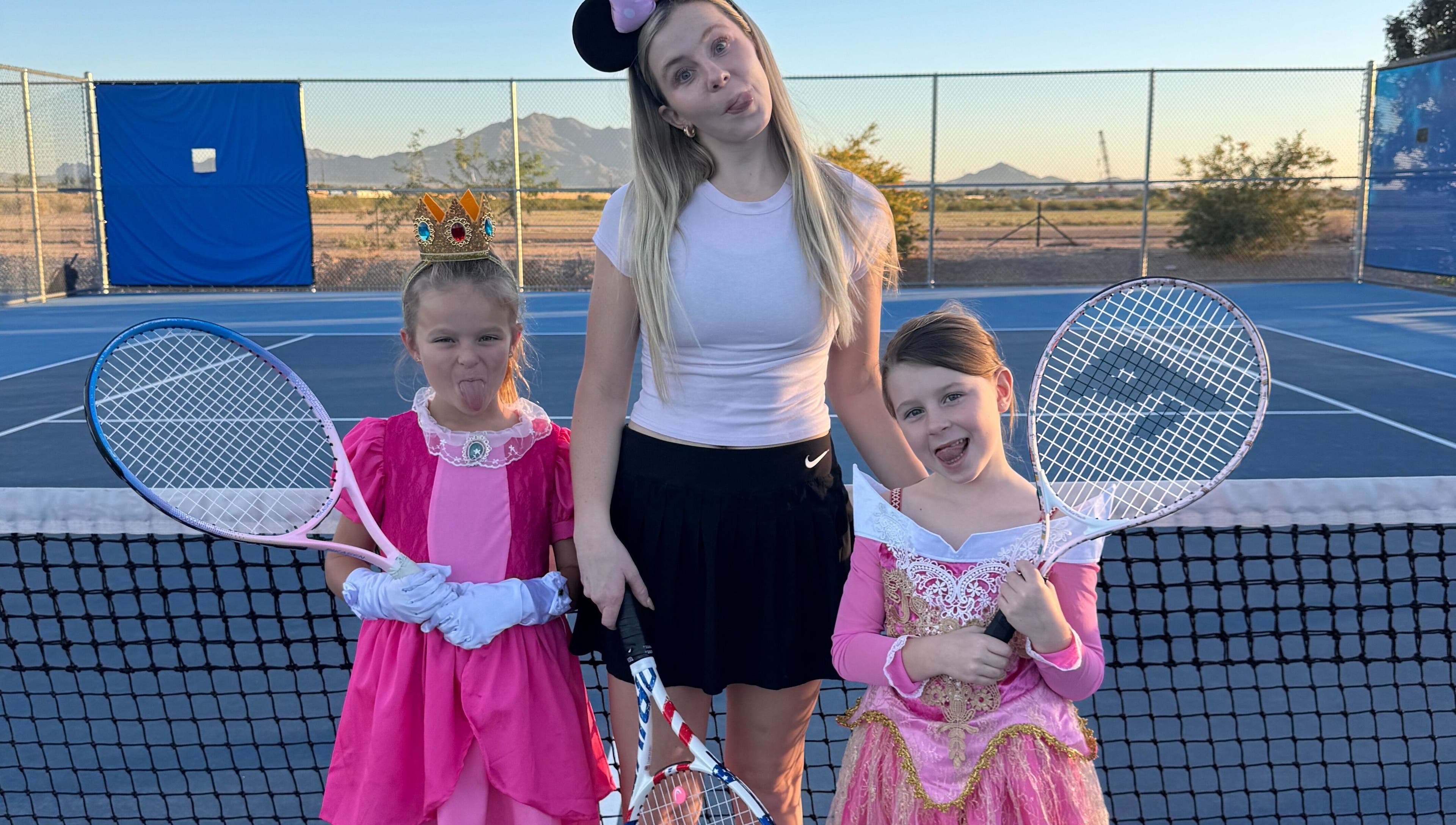 Children in princess costumes with tennis rackets at Racket & Paddle Club, Gilbert, Arizona, US.