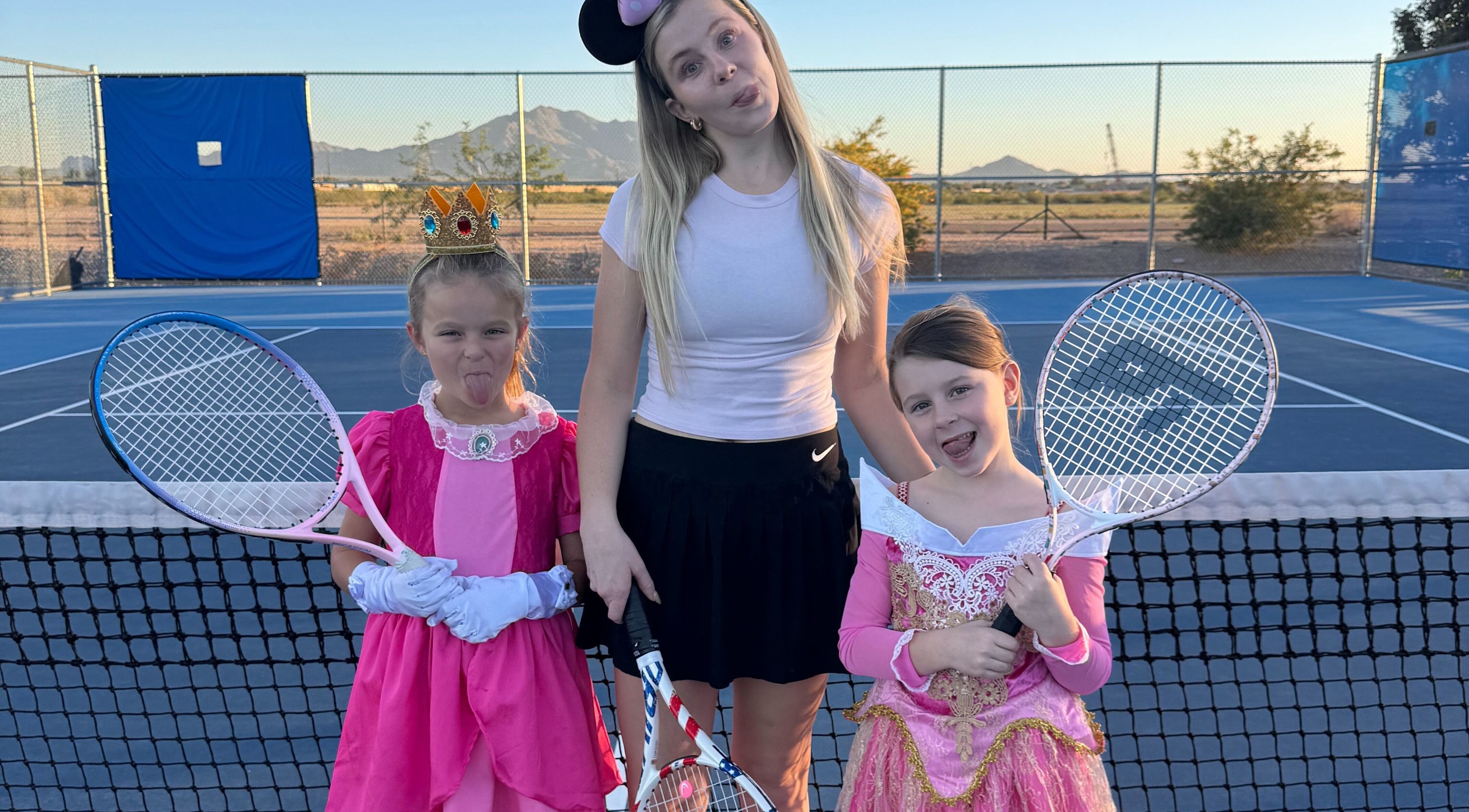 Children in princess costumes with tennis rackets at Racket & Paddle Club, Gilbert, Arizona, US.