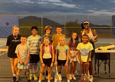 Children's tennis class at Racket & Paddle Club in Gilbert, Arizona, US, with instructor at sunset.