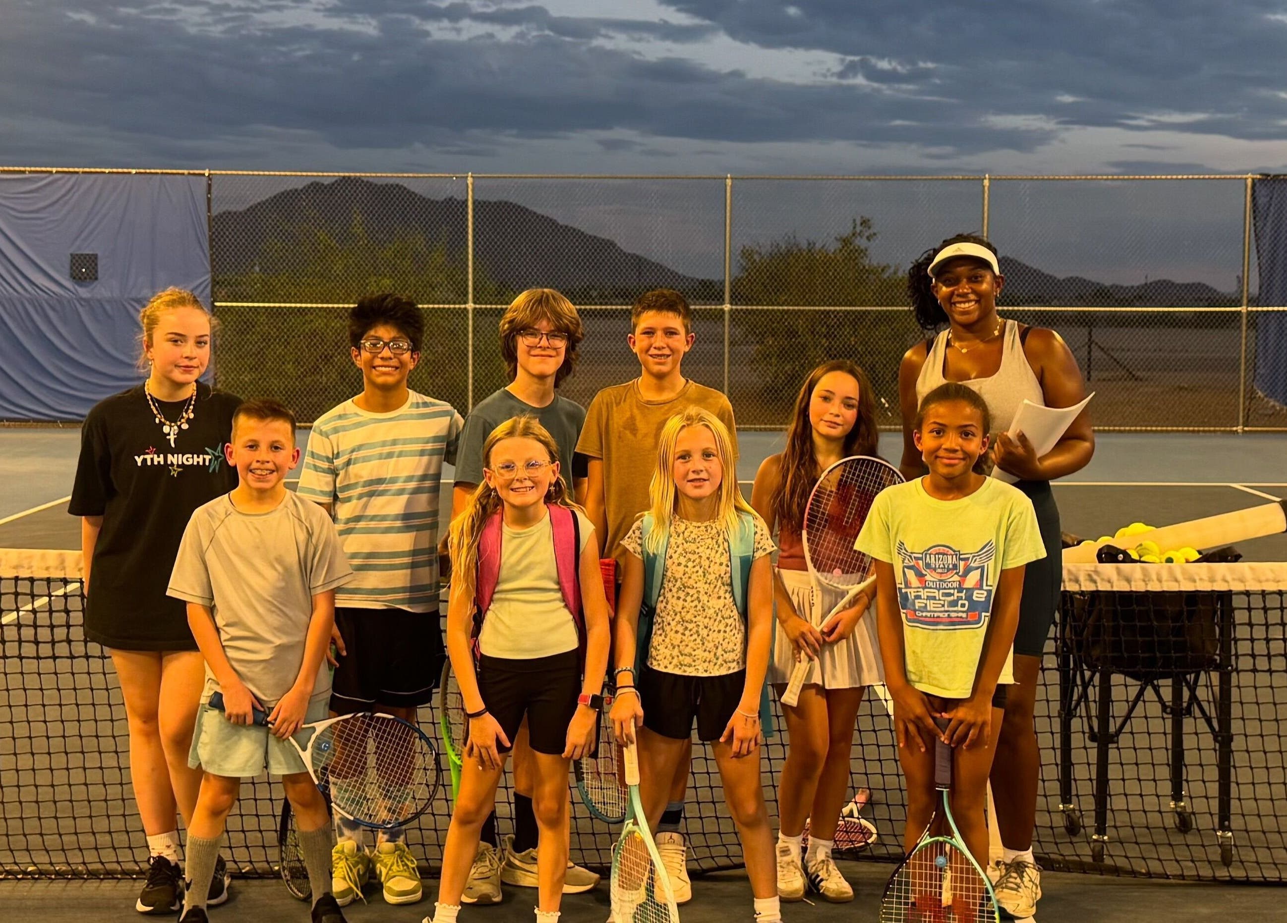 Children's tennis class at Racket & Paddle Club in Gilbert, Arizona, US, with instructor at sunset.