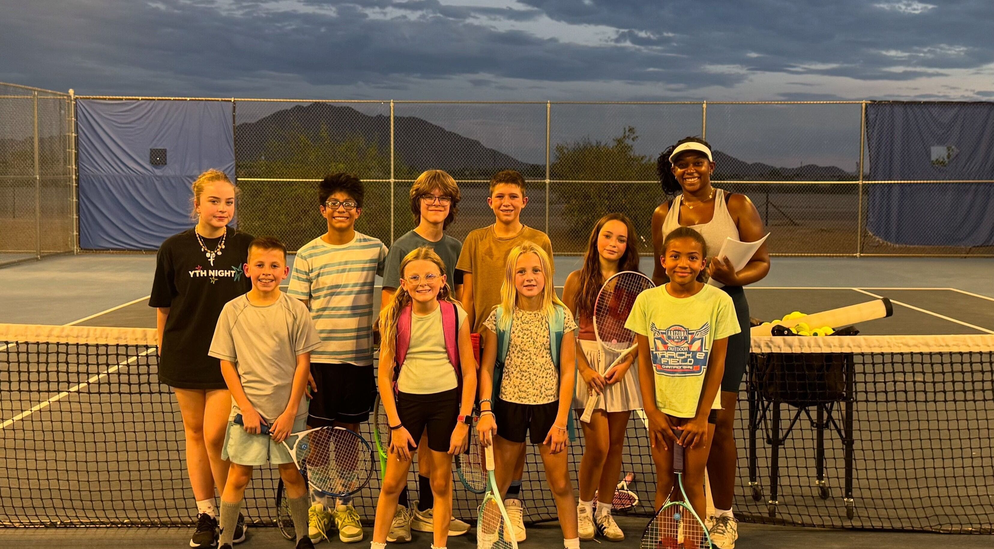 Children's tennis class at Racket & Paddle Club in Gilbert, Arizona, US, with instructor at sunset.