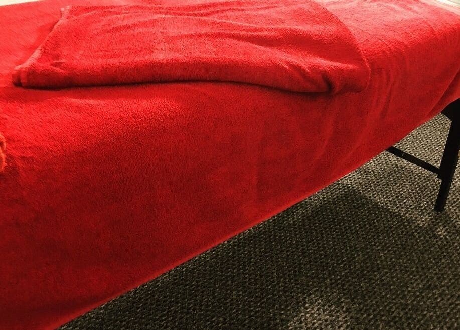 Cozy massage table with red towels at Sports Massage with E, Wellington, England, GB.