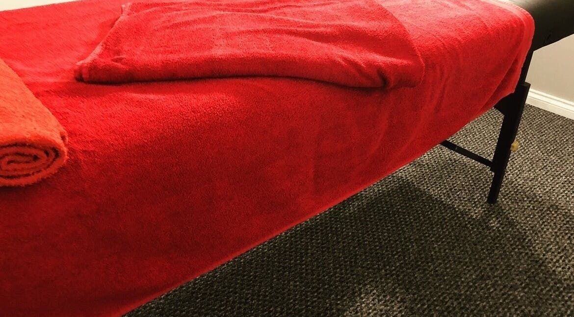 Cozy massage table with red towels at Sports Massage with E, Wellington, England, GB.